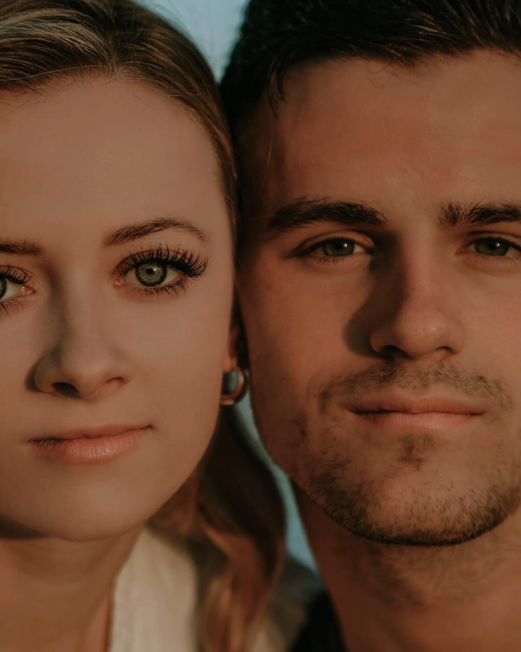 A close-up of a young woman and man, both with light skin, showing their faces and shoulders.