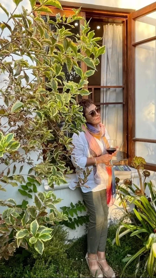 A woman standing on a garden balcony holding a glass of red wine in Chile wine country, part of a small group Chilean Wine Uncovered wine tour.