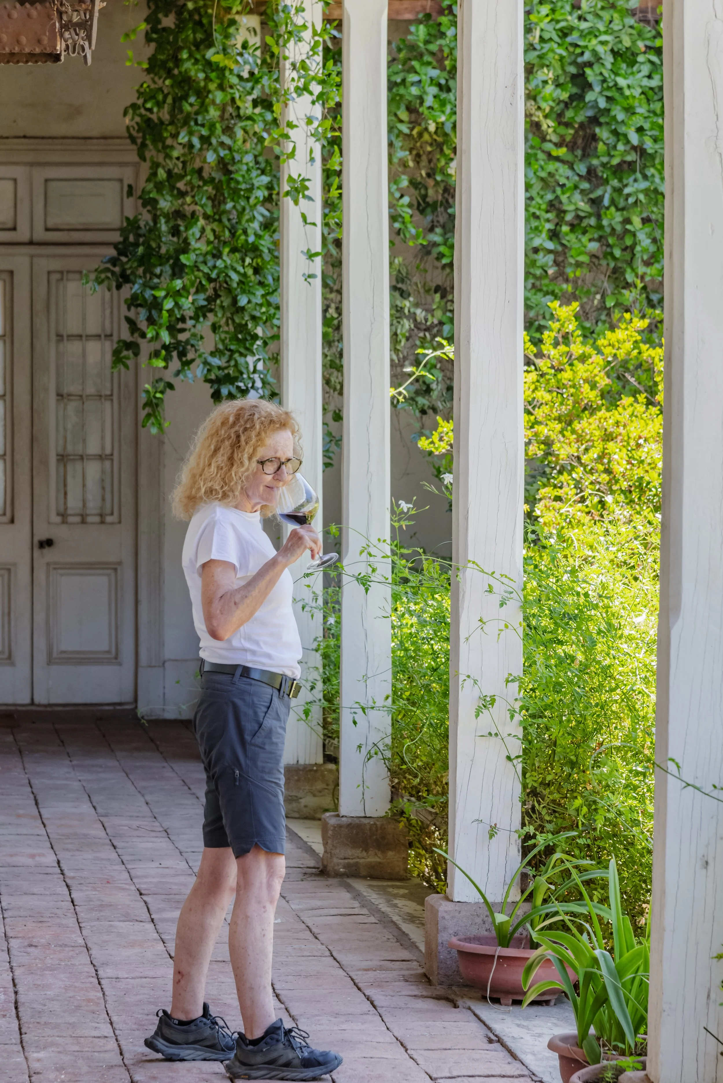 Popi Planella of Chilean Wine Uncovered standing on vineyard patio, enjoying a glass of red wine, during a tailored wine country tour of Chile.