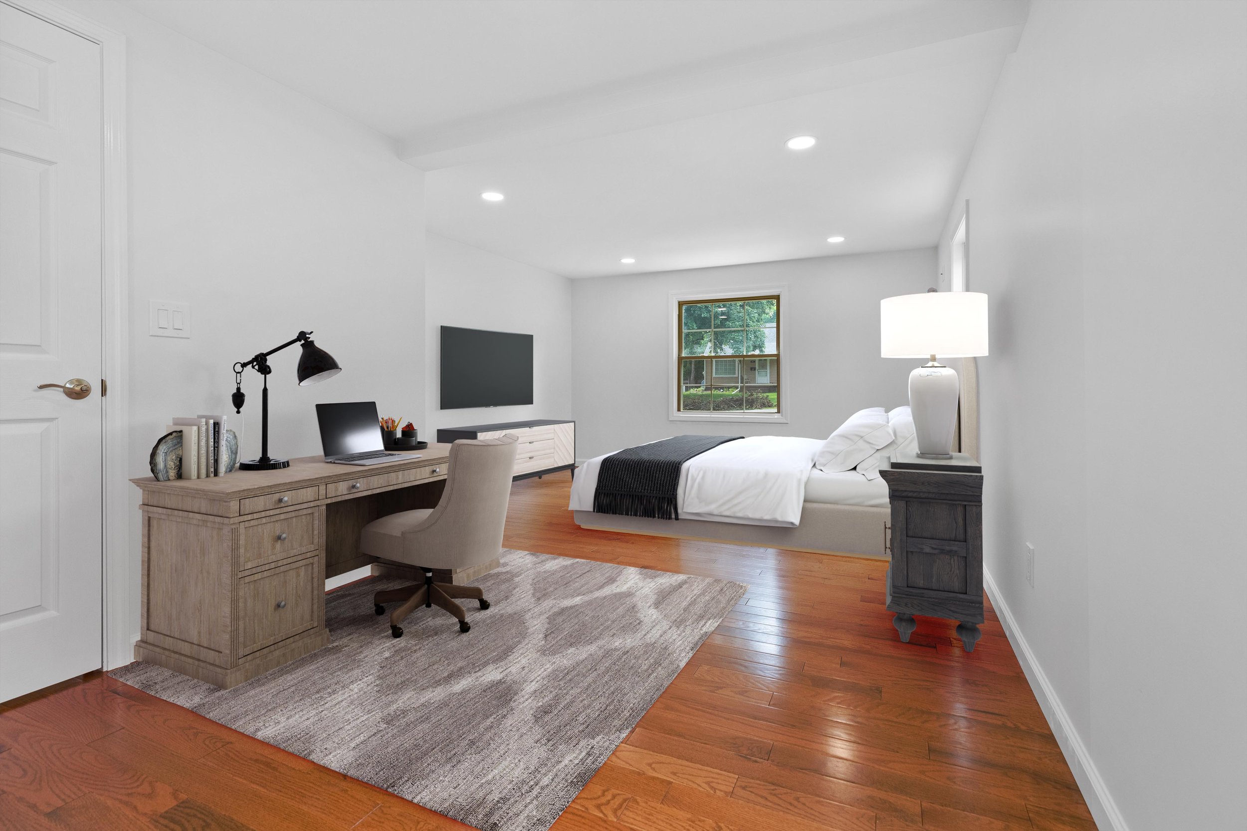 Spacious bedroom with a bed, desk, and TV, featuring white walls, hardwood floors, a window, and modern furnishings.