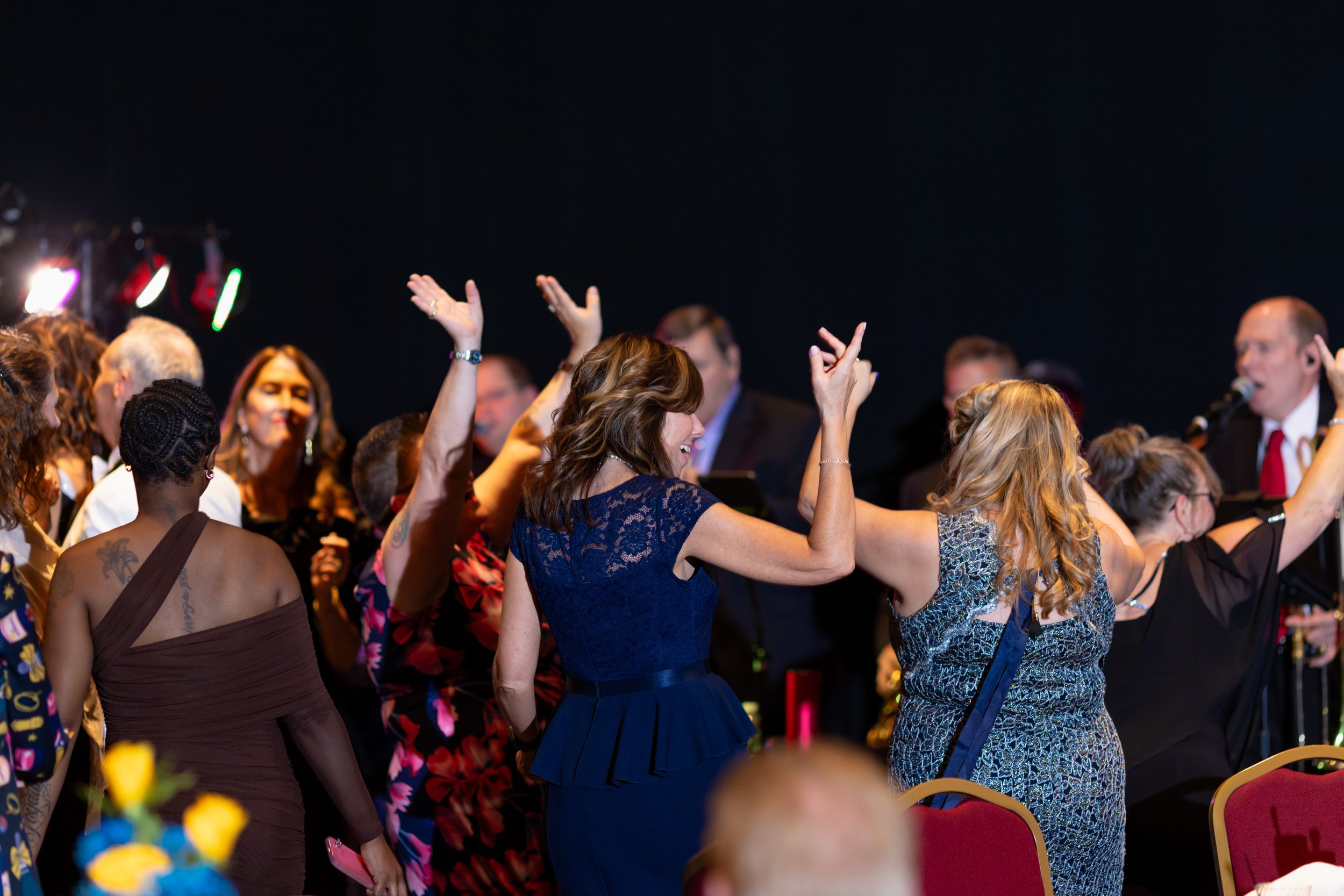 People dancing and enjoying music at a celebration or party in an indoor venue.