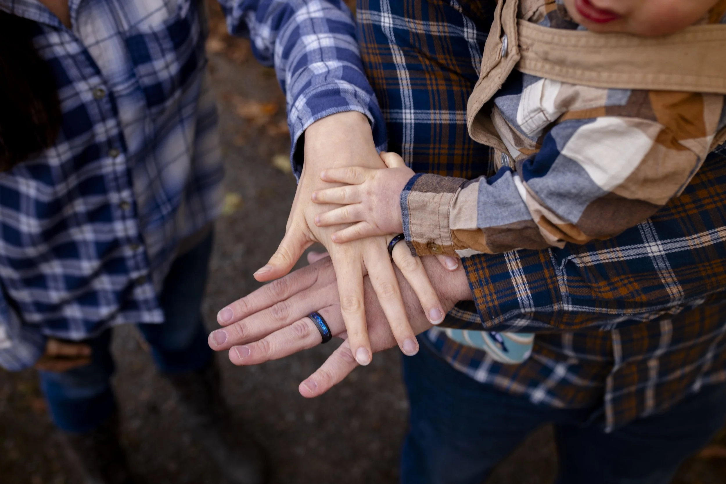 People holding hands in a group, with focus on one person displaying a black ring on their finger, outdoors.