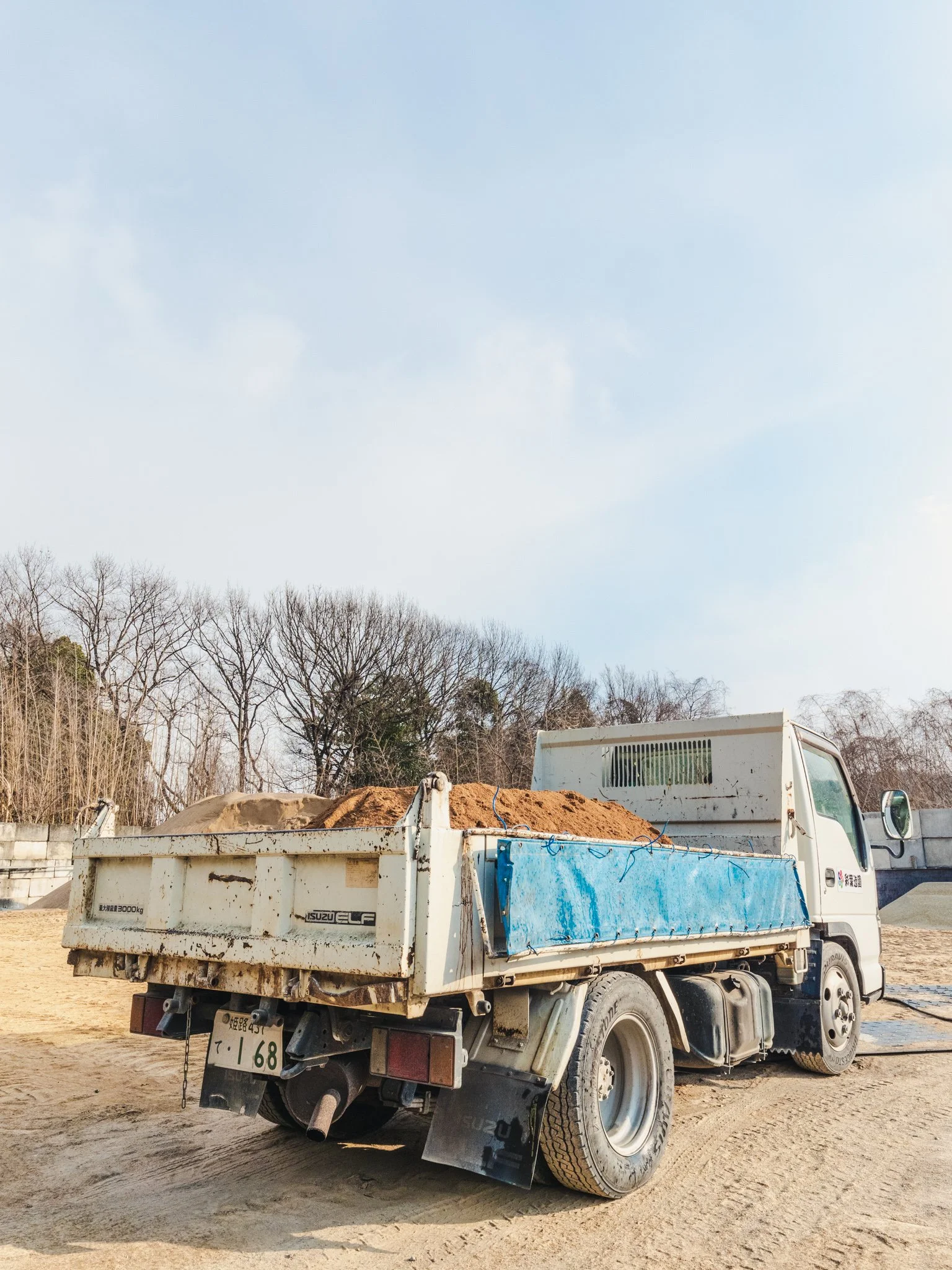 土が積み上げられた白いトラック