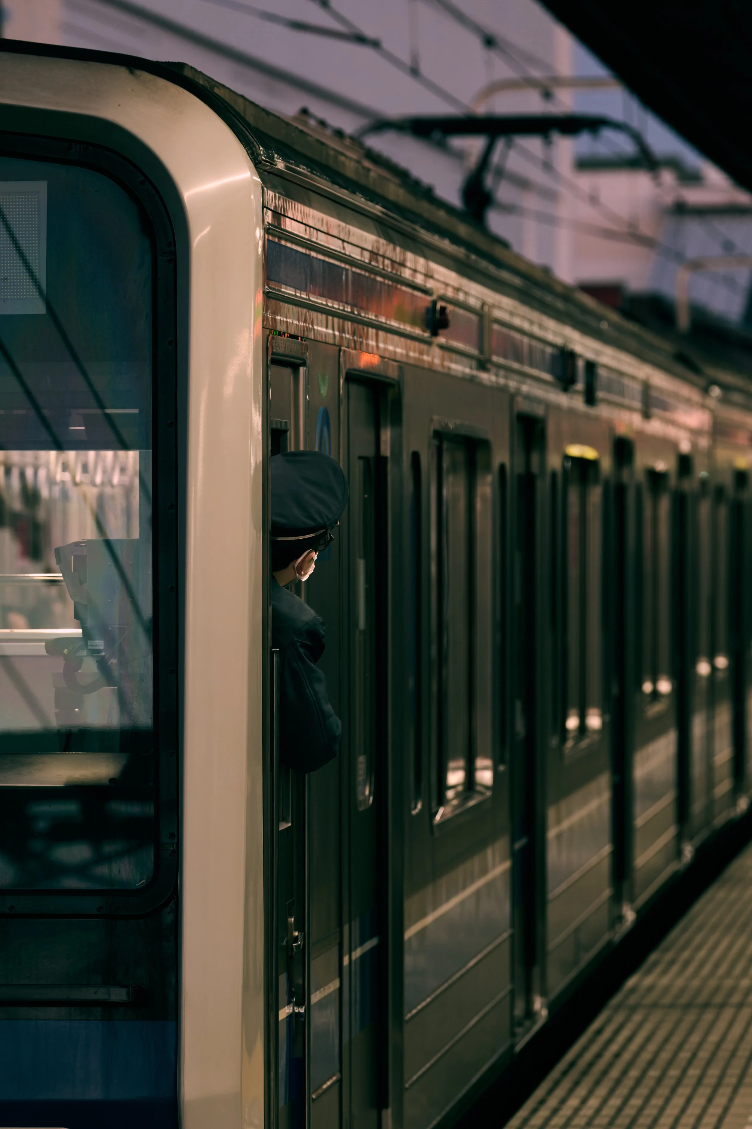 電車の側面に男性が帽子とマスクをつけて乗車している場面