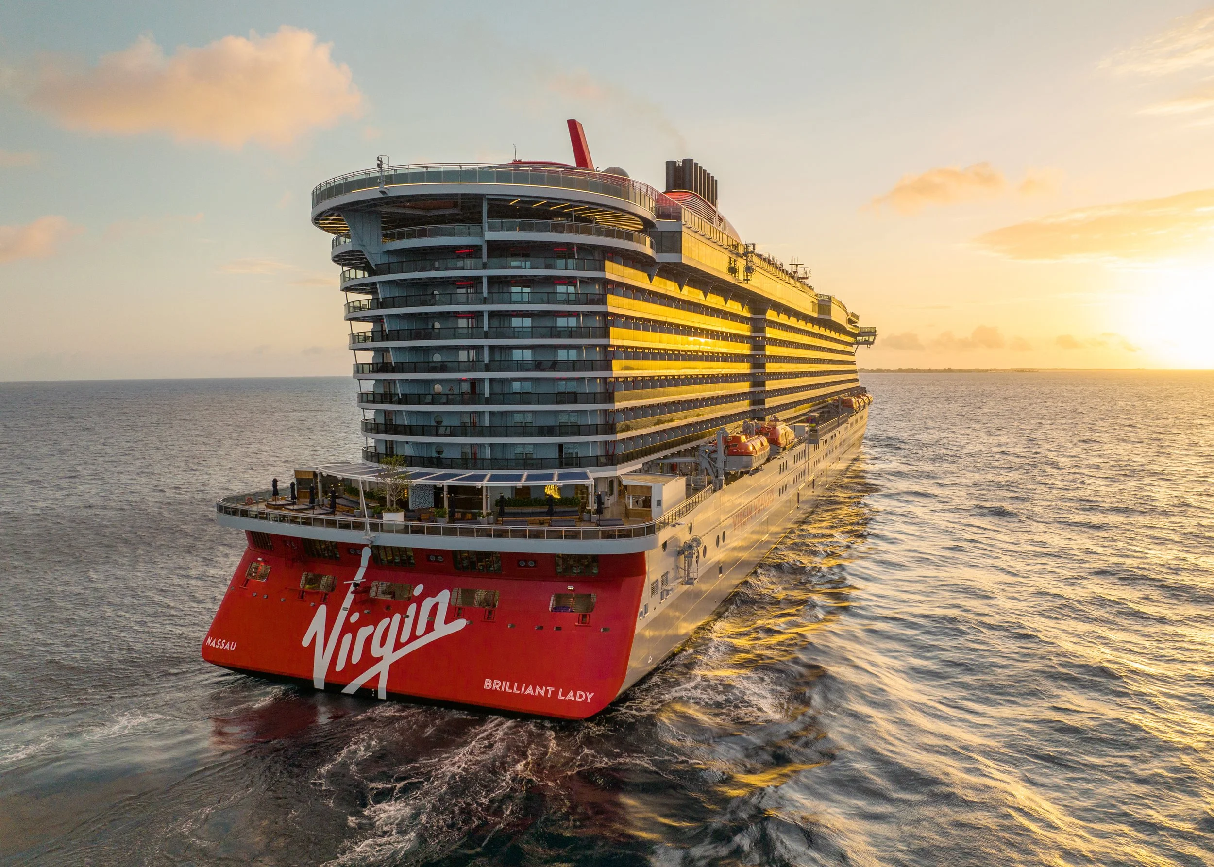 A large cruise ship named Virgin Brilliant Lady sailing on the ocean during sunset.
