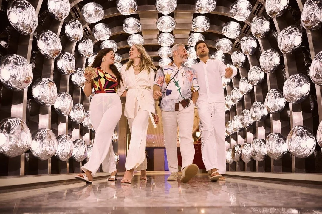 Four people walking through a hallway with rounded glass light fixtures on the wall, smiling and talking to each other.