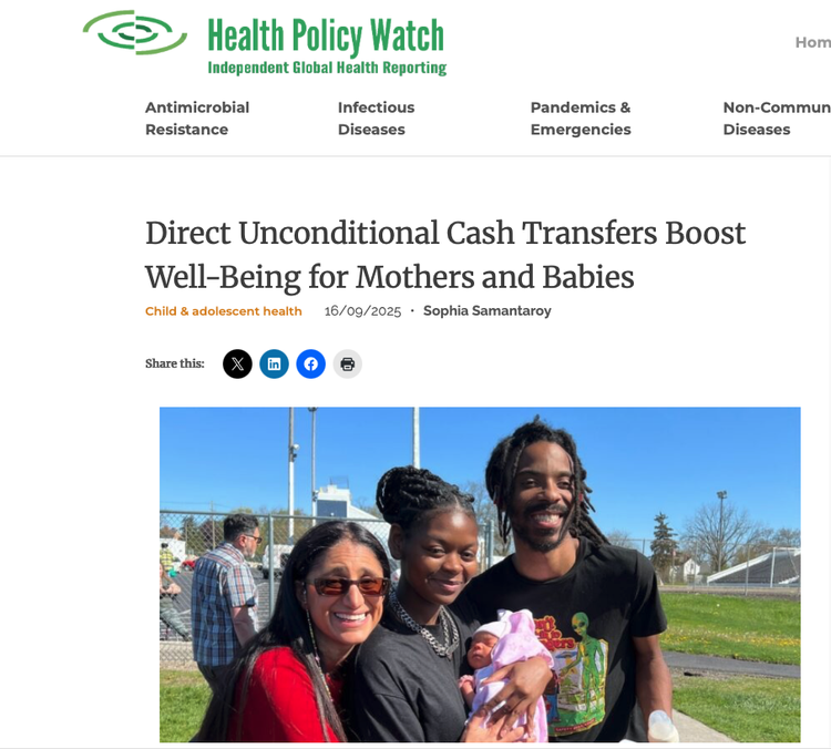 A group of three adults, two women and one man, smiling outdoors with a baby girl in a pink outfit and white hat, at a park with a chain-link fence and blue sky in the background.