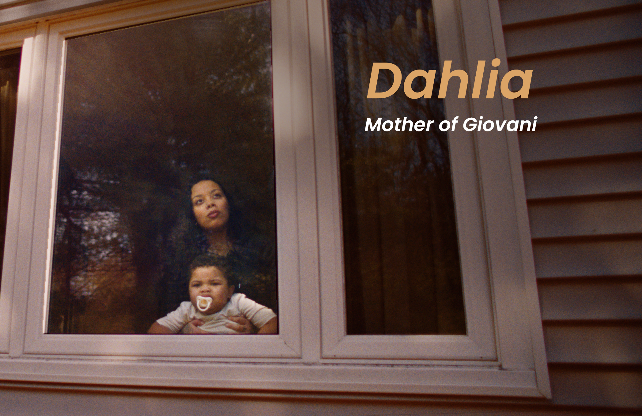 A woman and a baby are looking out a window. The woman has long dark hair, and the baby is using a pacifier.