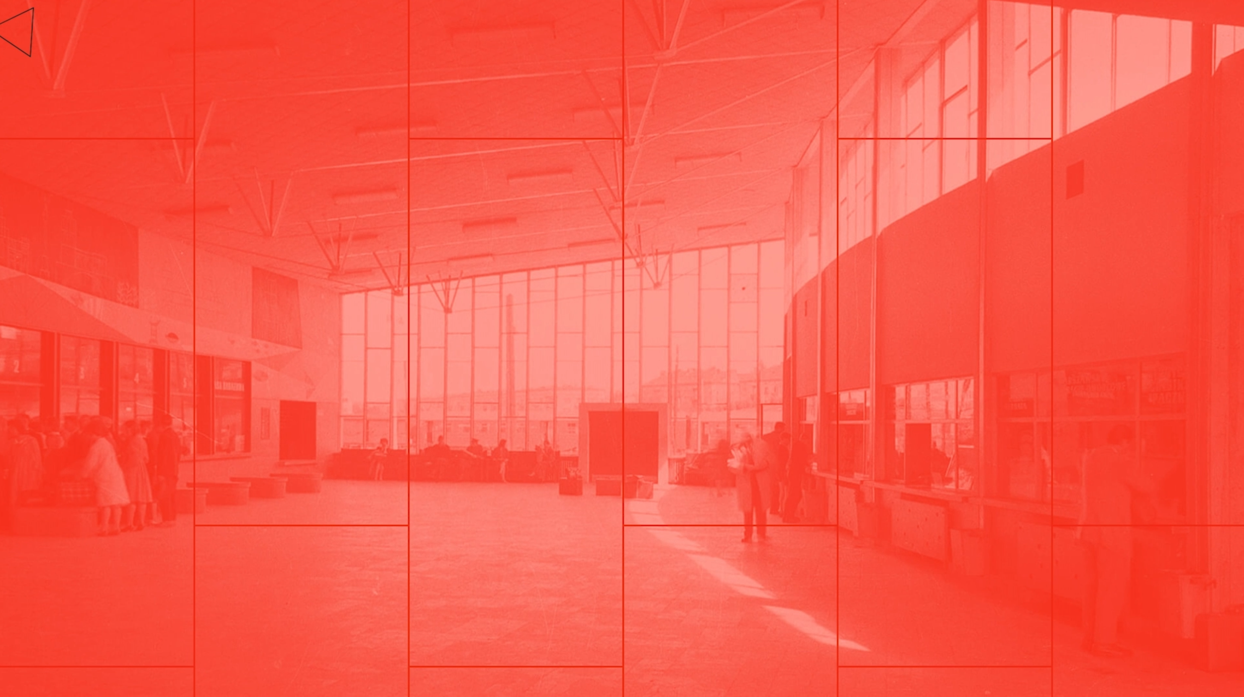 Interior of a large modern airport terminal with high ceilings, large windows, and people waiting in line or sitting.