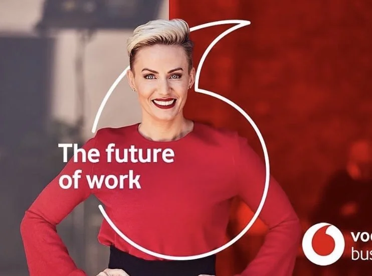 A woman with short blonde hair wearing a red top, smiling confidently, with a red background and white text that says "The future of work" and a partial logo in the corner.
