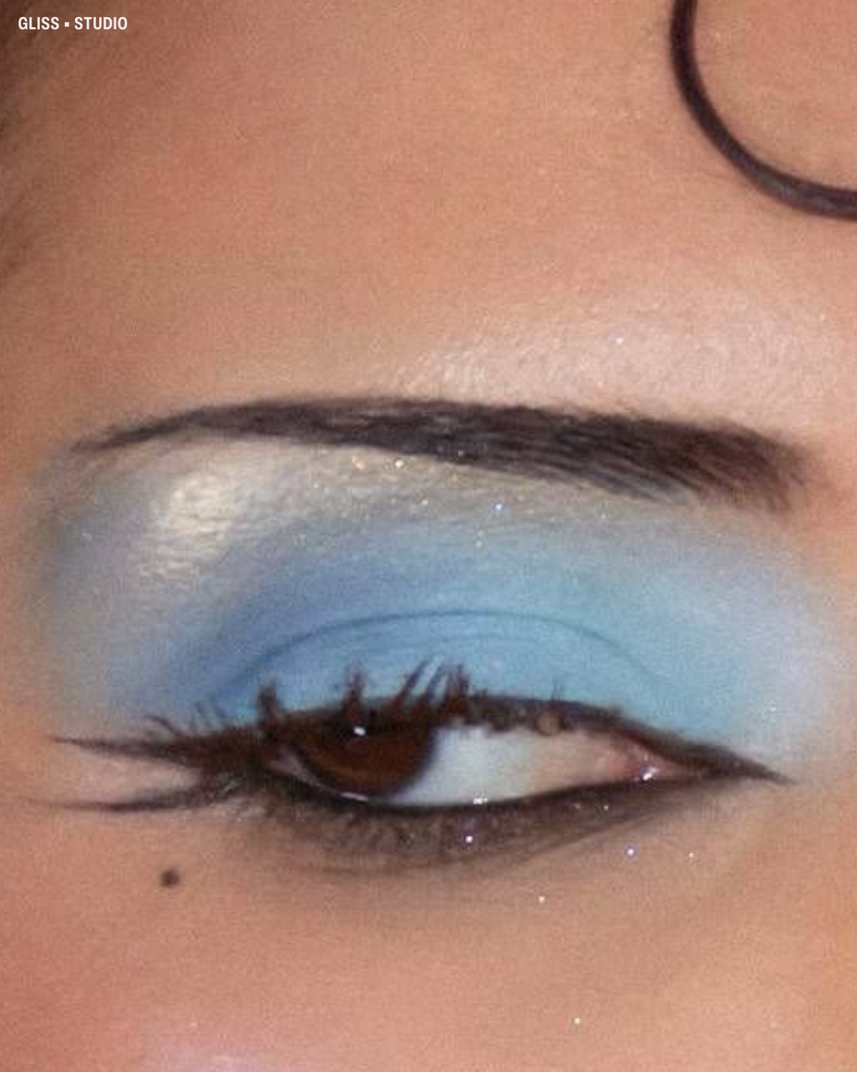 Matte sky blue eyeshadow on the lids, palest blue shimmer on the brow bone of a brown eye with winged liner.