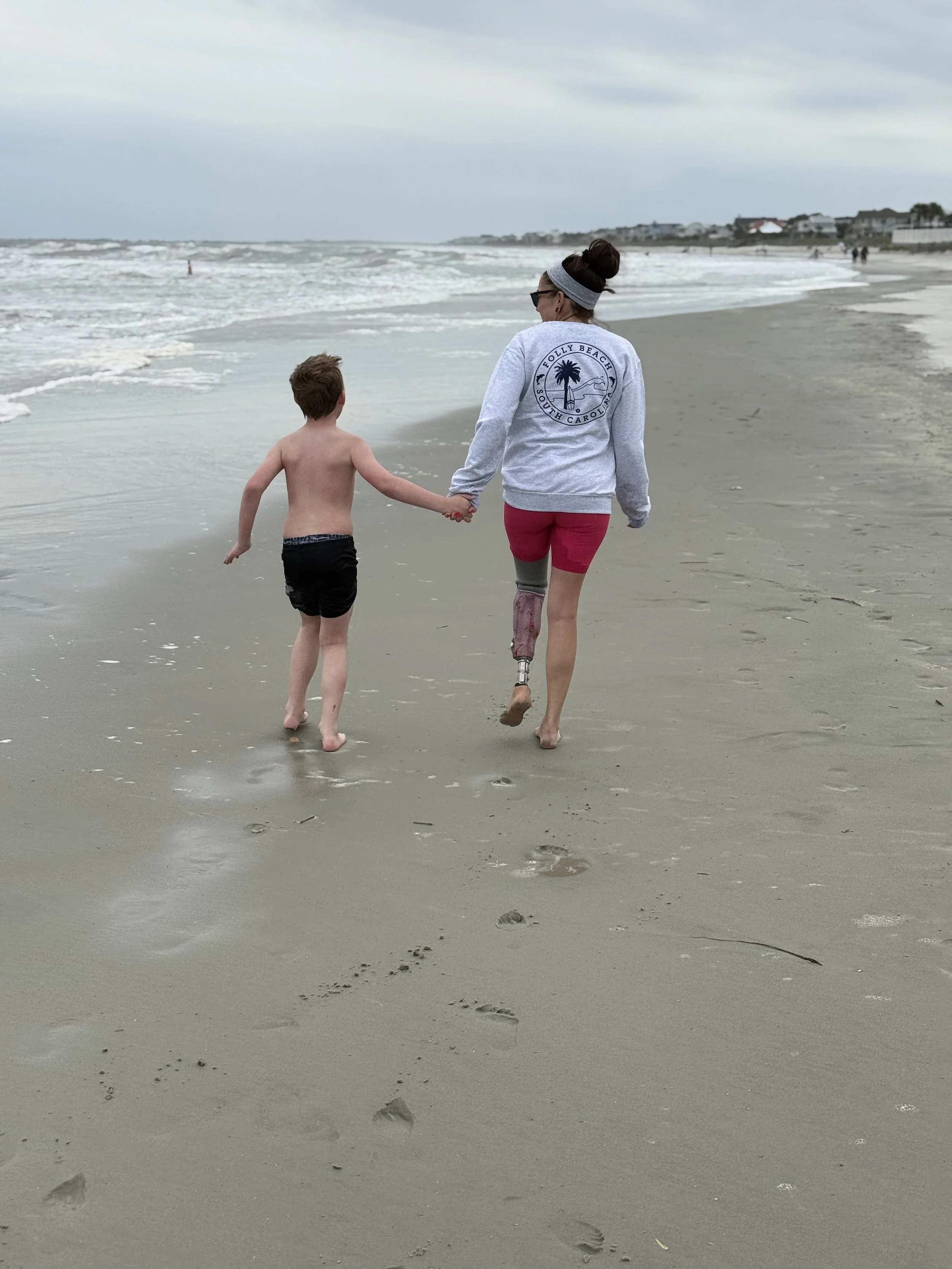 female amputee walking on the beach with child