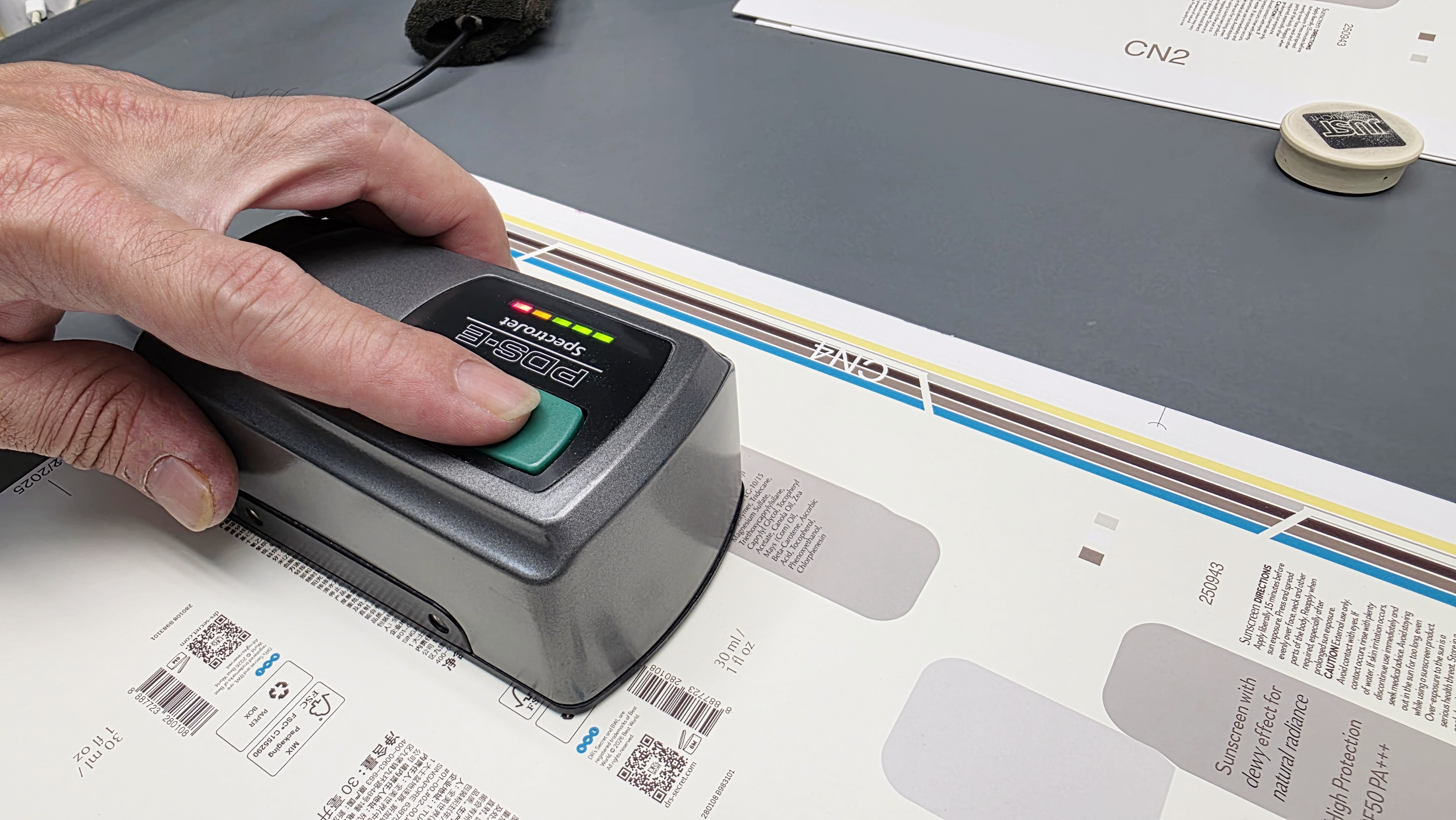 Handheld colour measurement device checking printed sheets to ensure colour accuracy, consistency, and print quality control.​