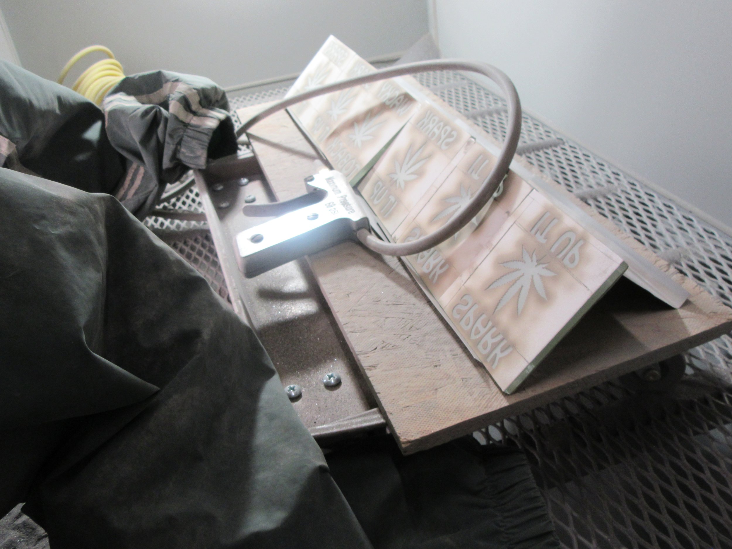 Inside cabinet view.- shows modified protective sleeves, specialized blasting gun, blasting easel on rolling cart.