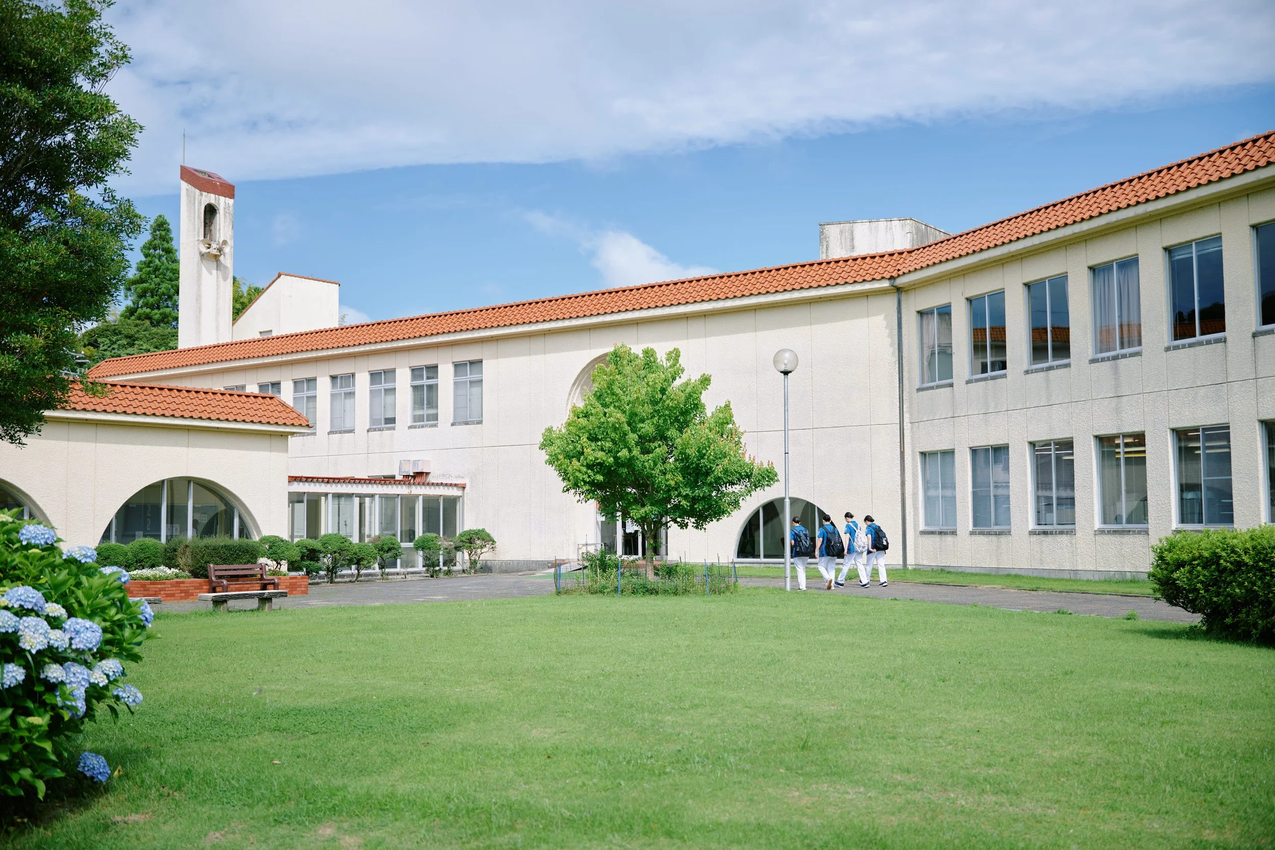 学校の校舎と中庭にいる学生のグループ