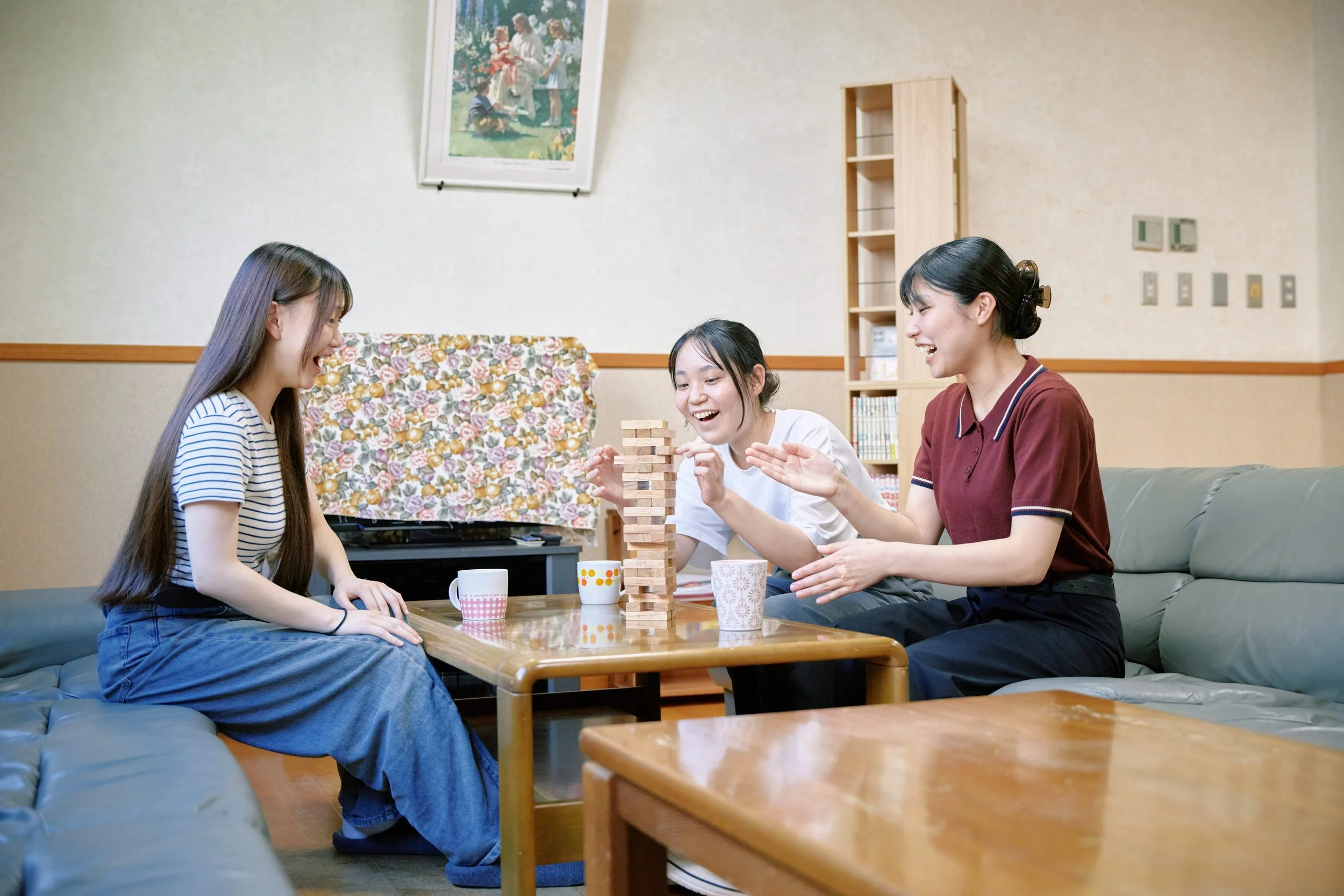 四人の若い女性がリビングルームでテーブルを囲み、ジャングルゲームを楽しんでいる。