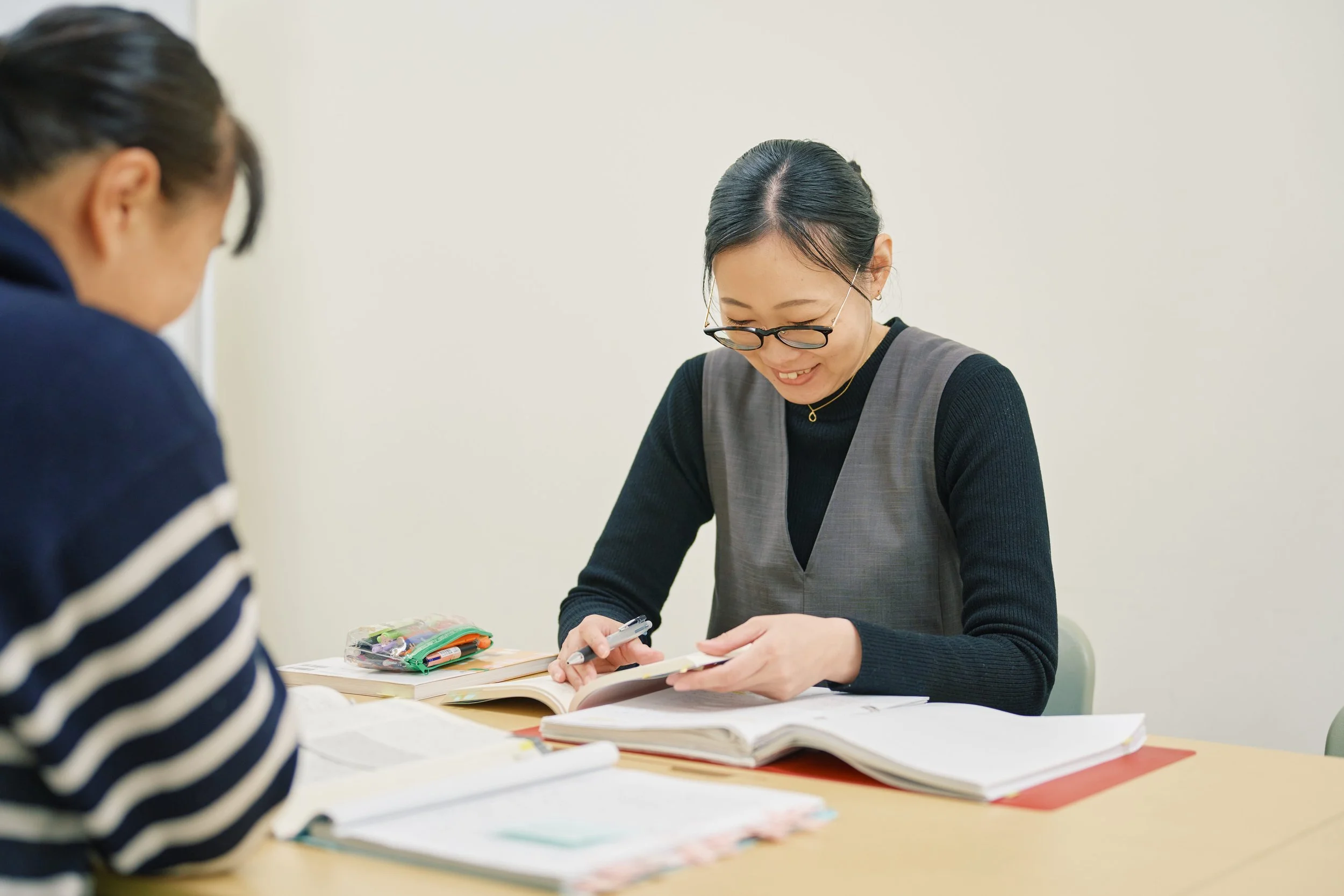 二人の女性がテーブルで勉強または作業をしている。」}