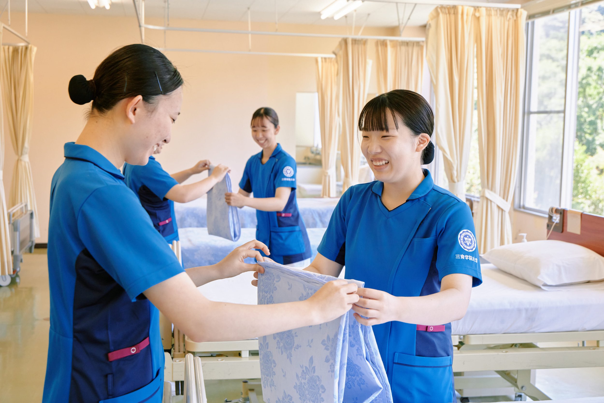 看護学校の学生たちが患者のためのシーツ交換を行っているシーン