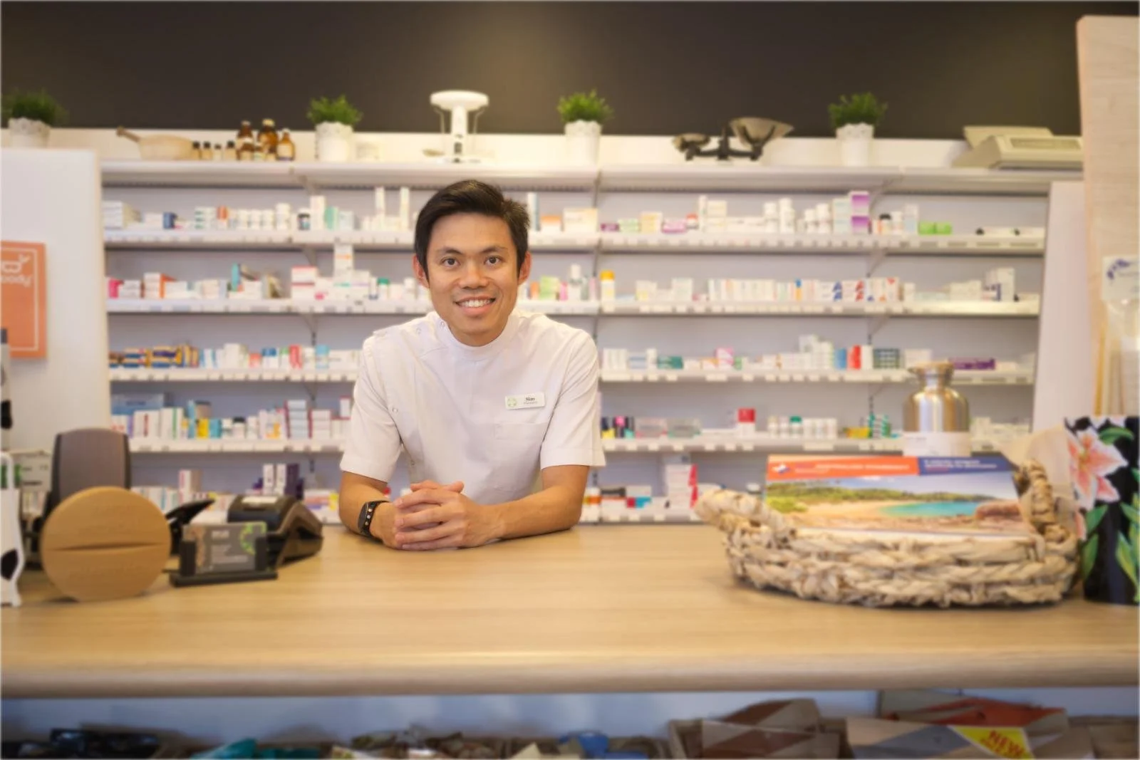 Pharmacist Sim Lee standing behind the dispensary counter in Trigg
