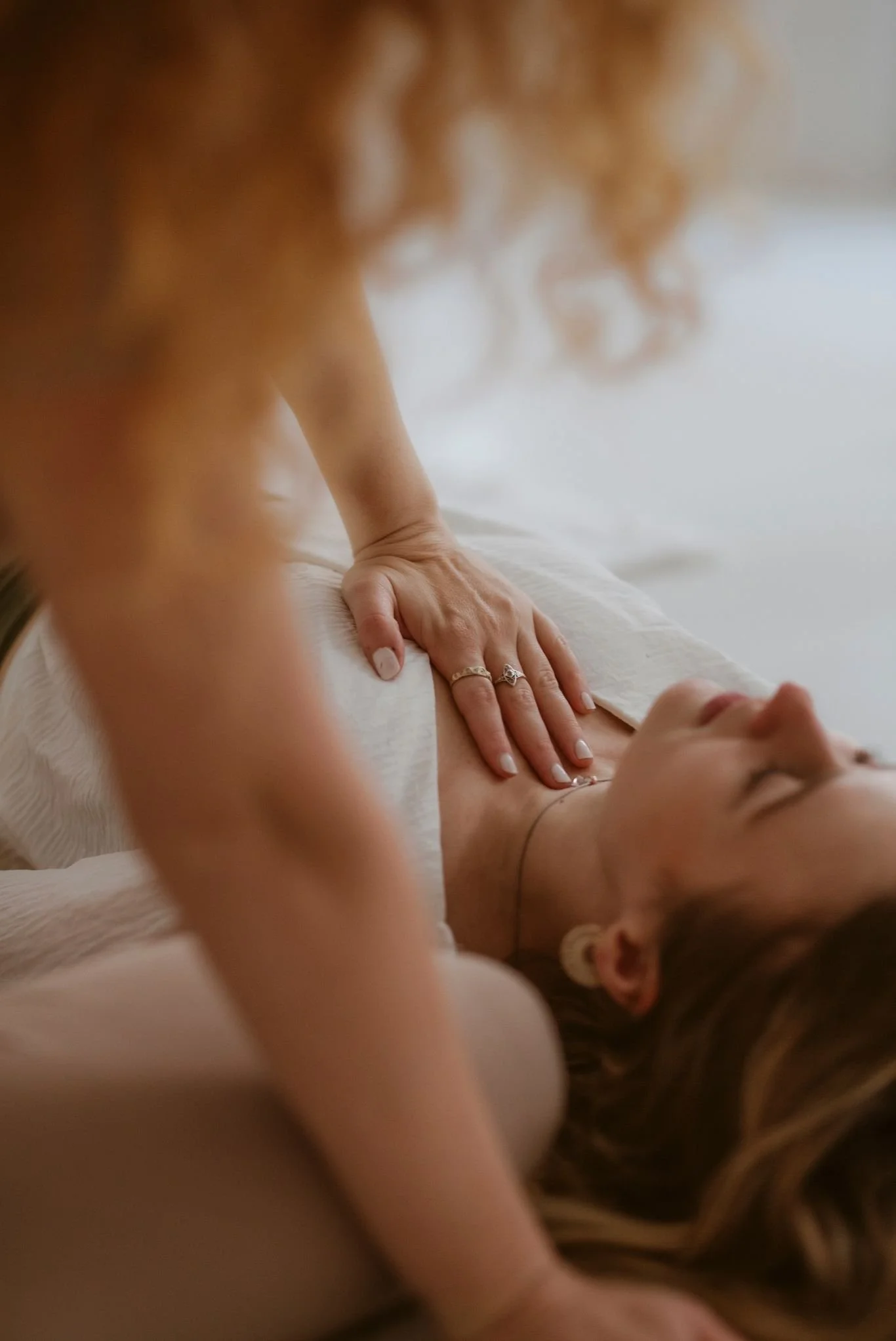 Nahaufnahme eines Körpers während einer Akupunktursitzung, Fokus auf Hand mit Ringen, die auf den Brustkorb einer liegenden Person zeigt, mit Nadeln in der Haut.