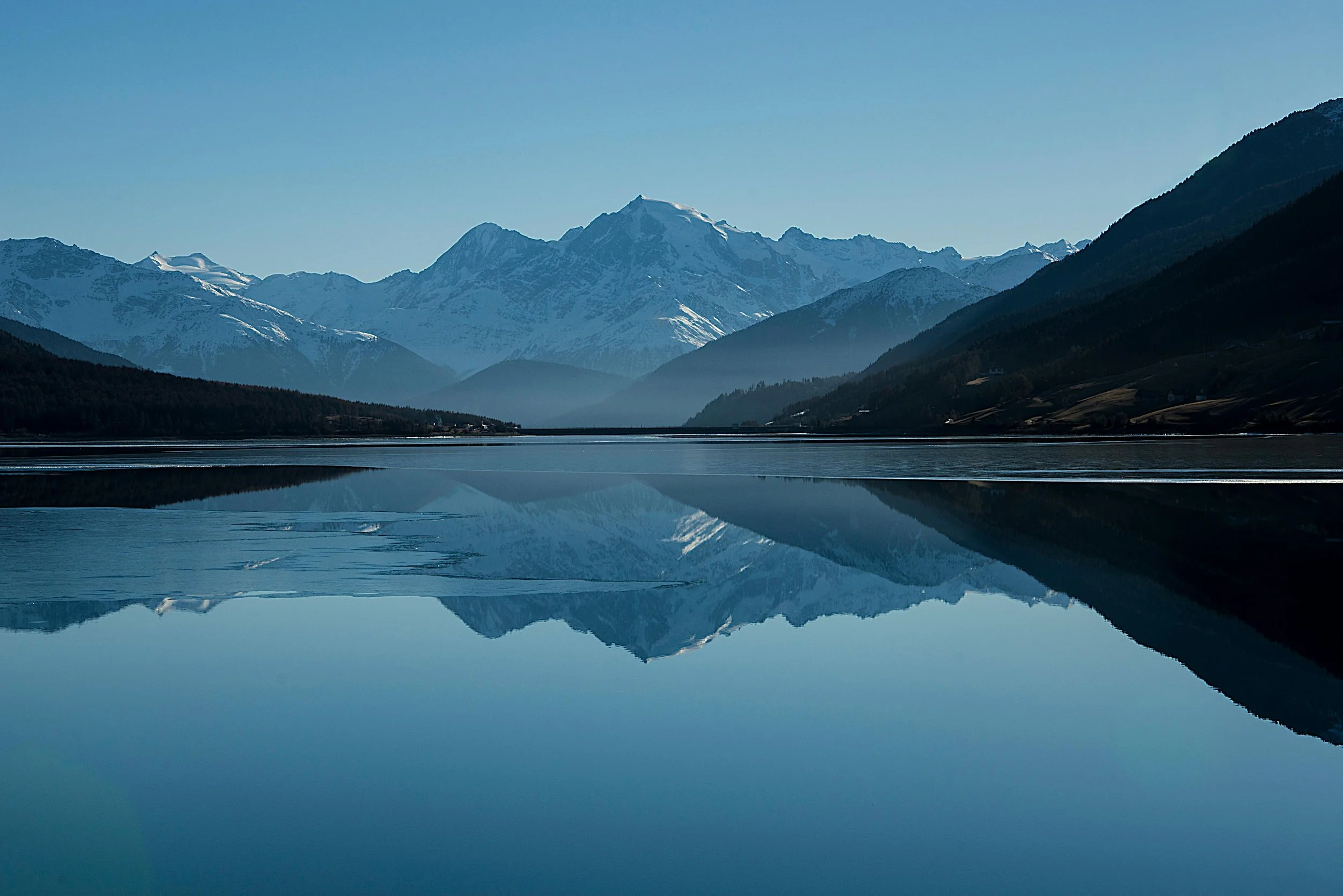 Snow-capped mountains reflected in a calm lake symbolising clarity, long-term vision, and strategic growth supported by Scale Up Partners.