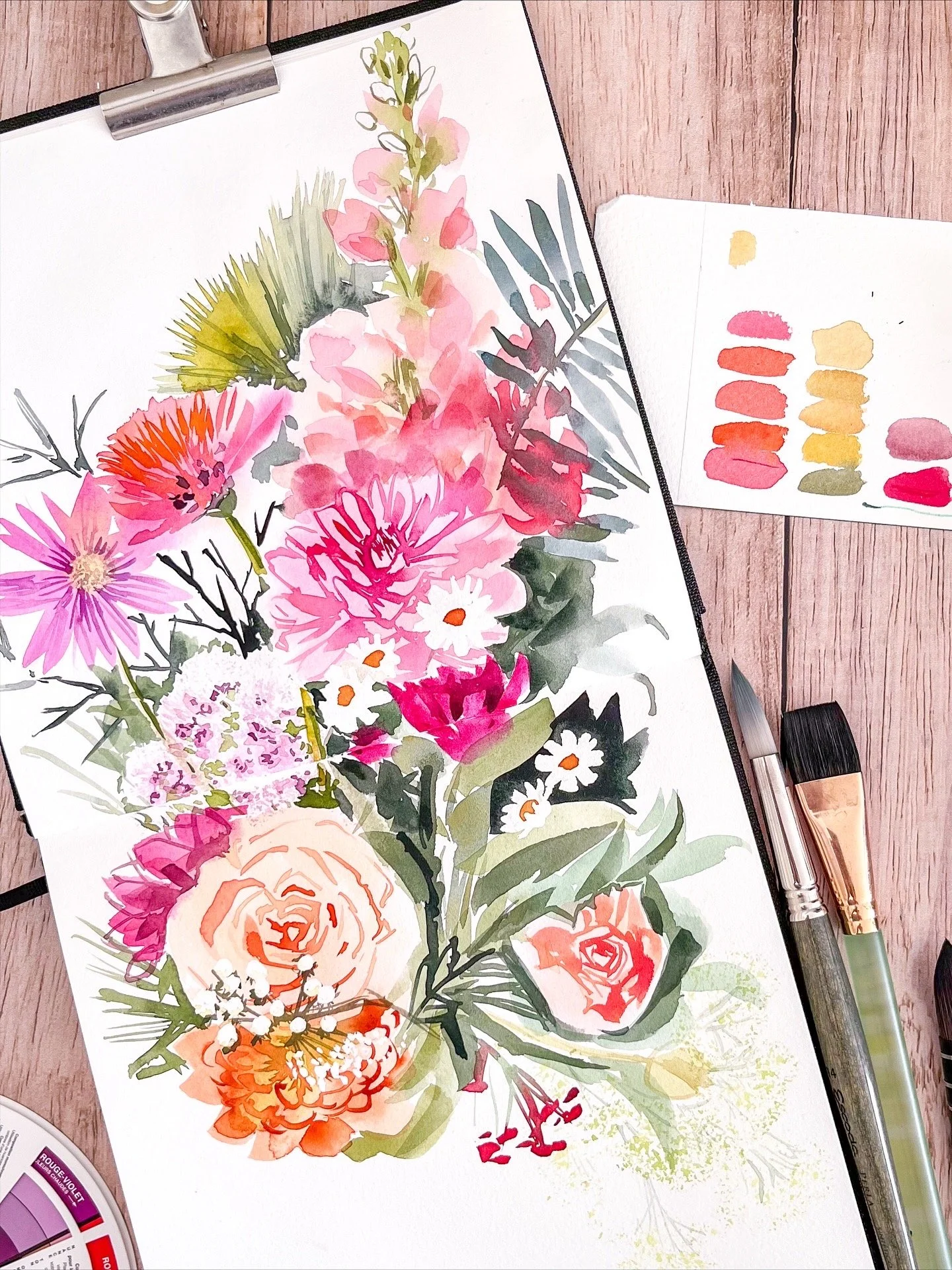 Peinture aquarelle d'un bouquet de fleurs colorées, avec des pinceaux et une palette de couleurs à côté.