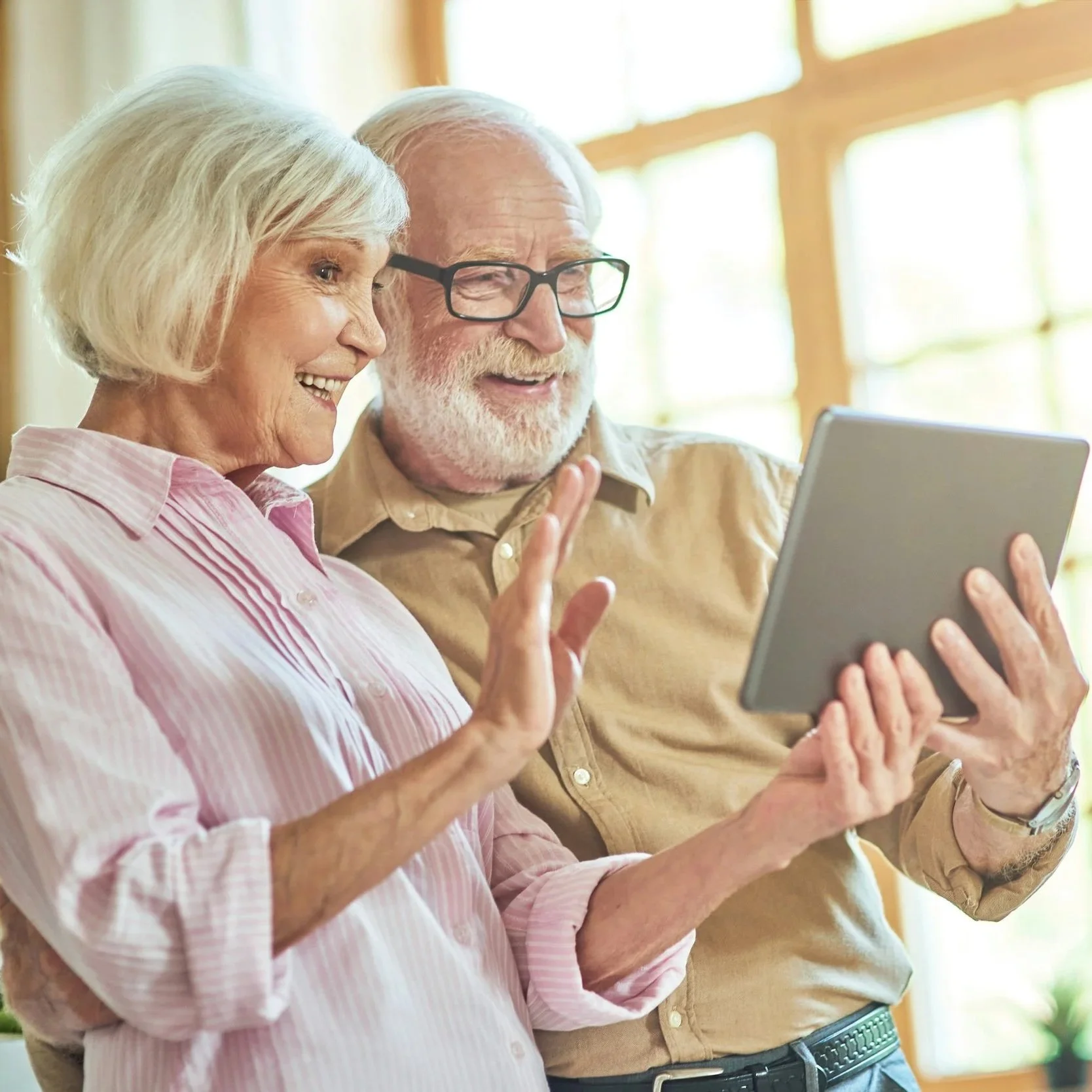 An elderly couple looking at a tablet device together and smiling.