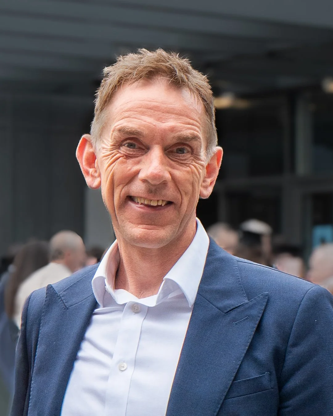 Andy Falconer - smiling middle-aged man wearing a dark blue suit and white shirt at a social event.