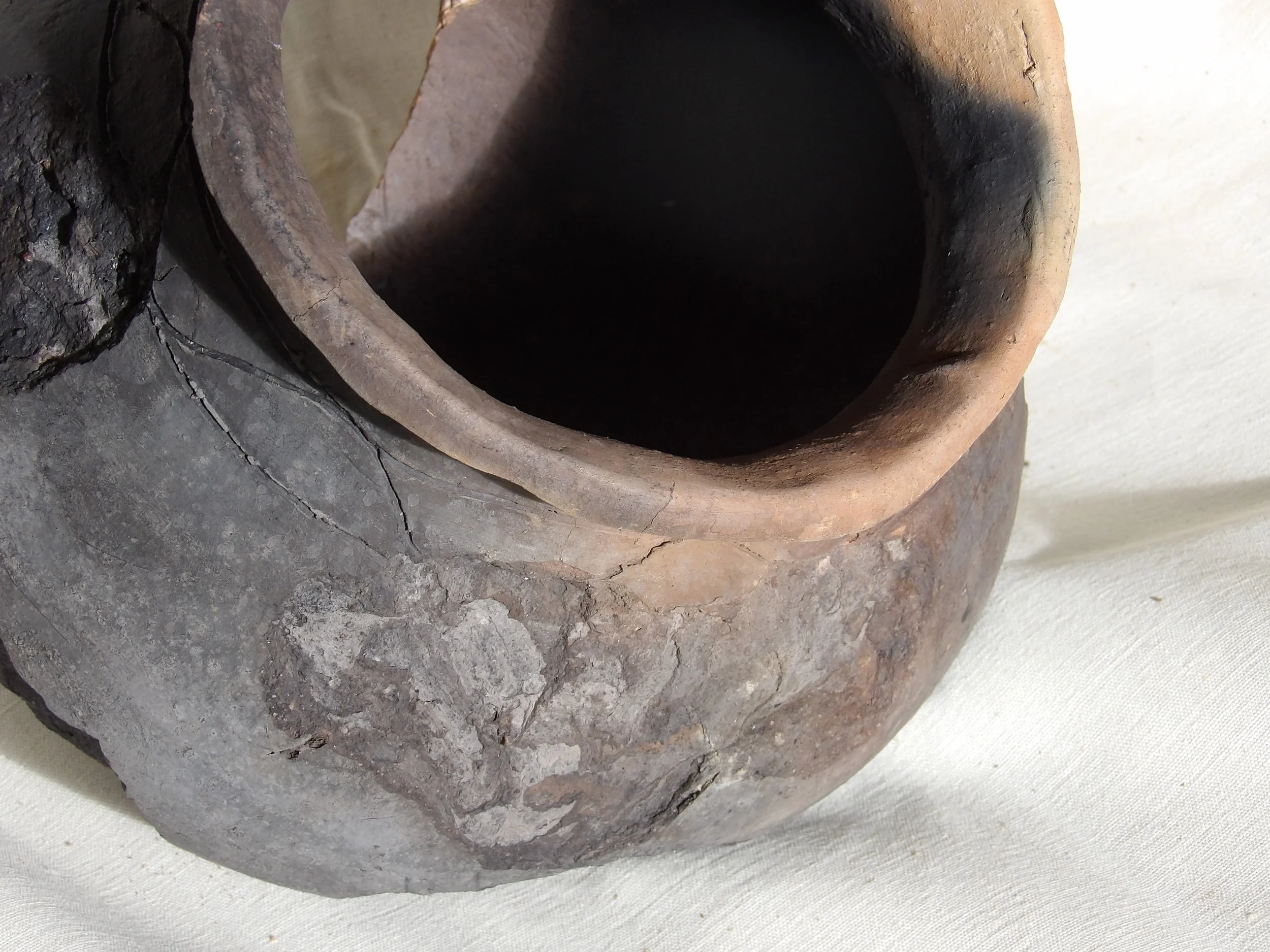 The surface bears traces of hand compression and burnishing, with uneven tonal shifts produced through open firing.