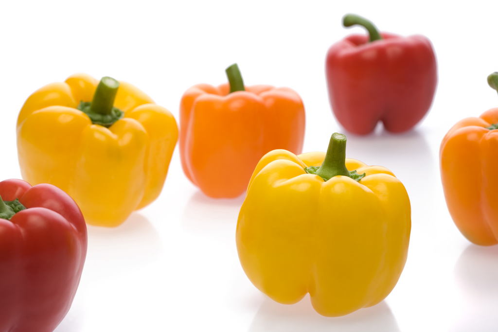 A group of colorful bell peppers including yellow, orange, and red, arranged on a white background.