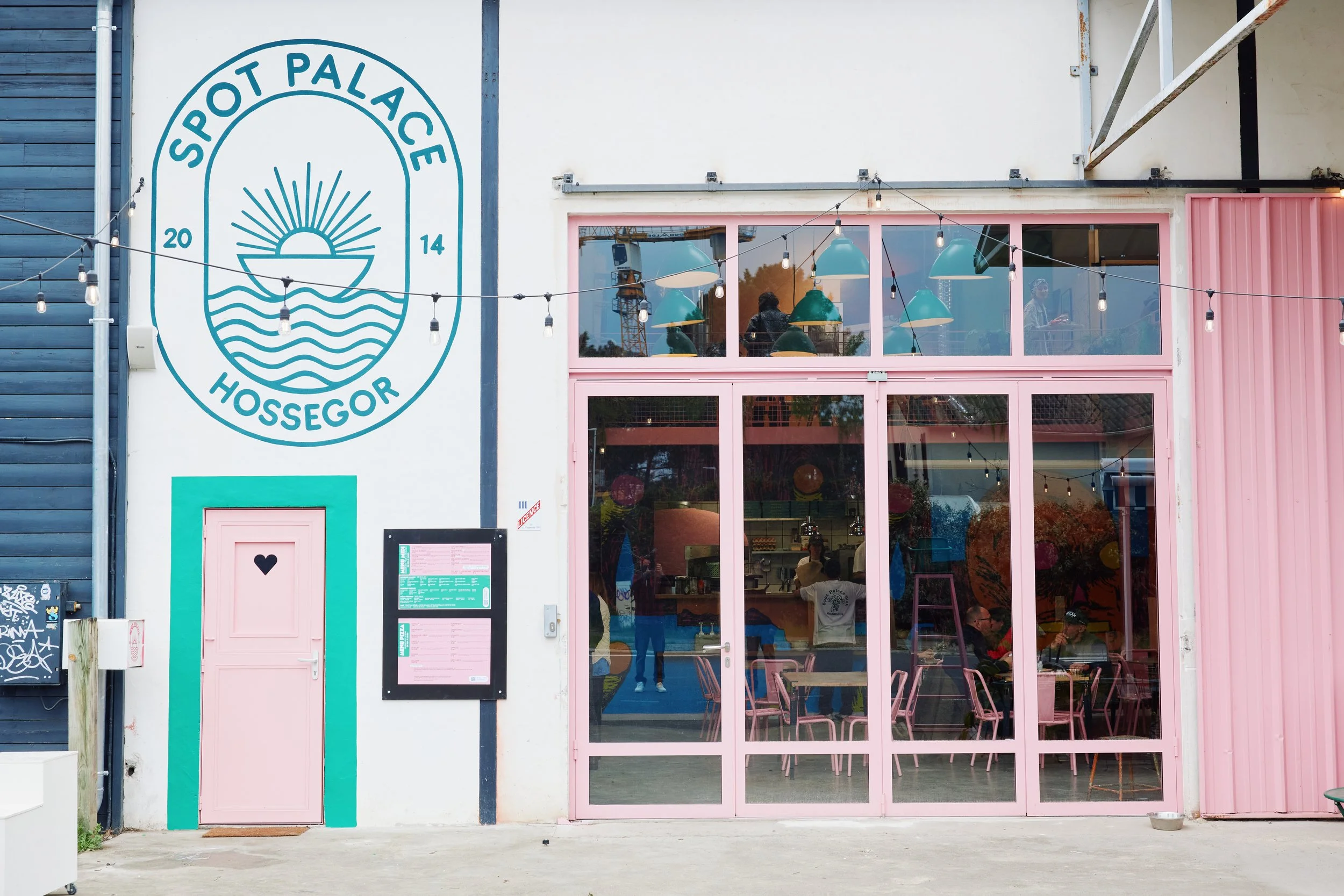 Façade coloré du coffee shop / restaurant  'SPOT PALACE HOSSEGOR' et un logo de soleil et vagues.