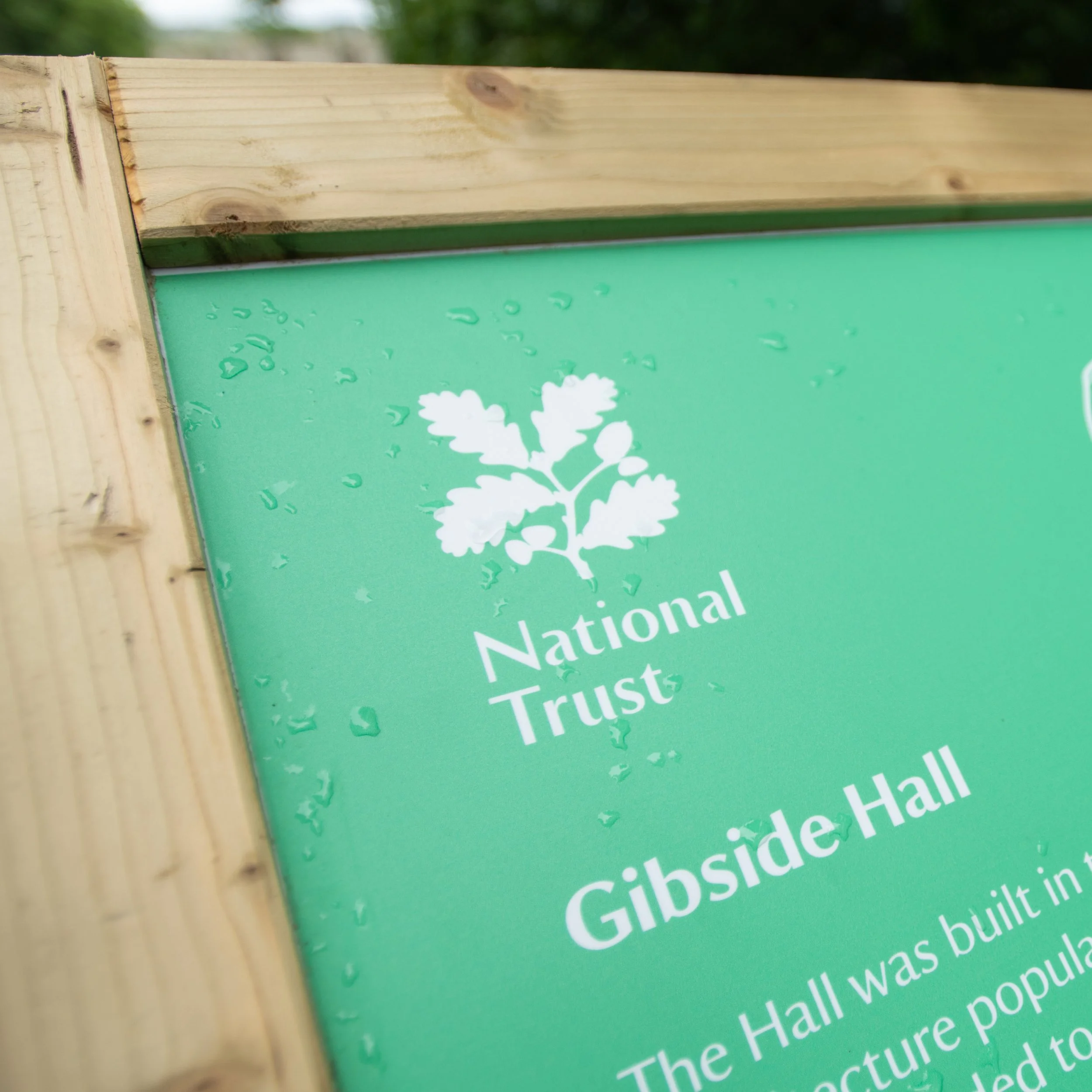 A close up image of an interpretation panel at National Trusts Gibside estate. The panel is green and shows the National Trust logo with some text about Gibside Hall.