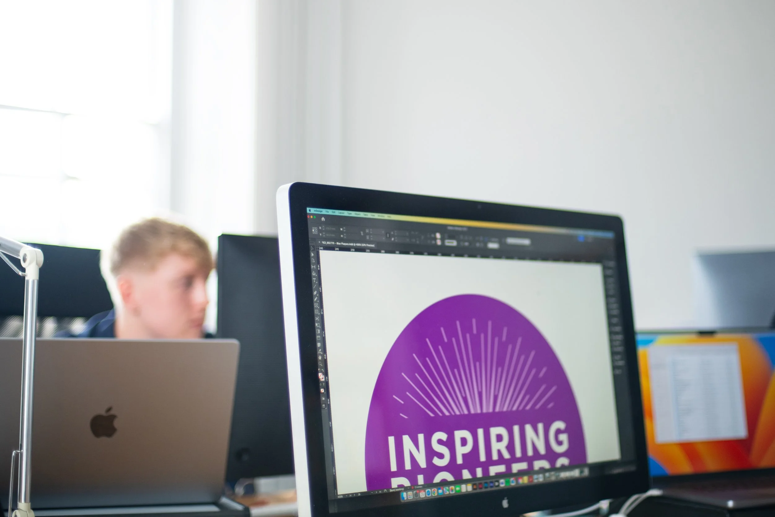 Computer monitor displaying a purple logo with white text that reads 'Inspiring' in an office setting.