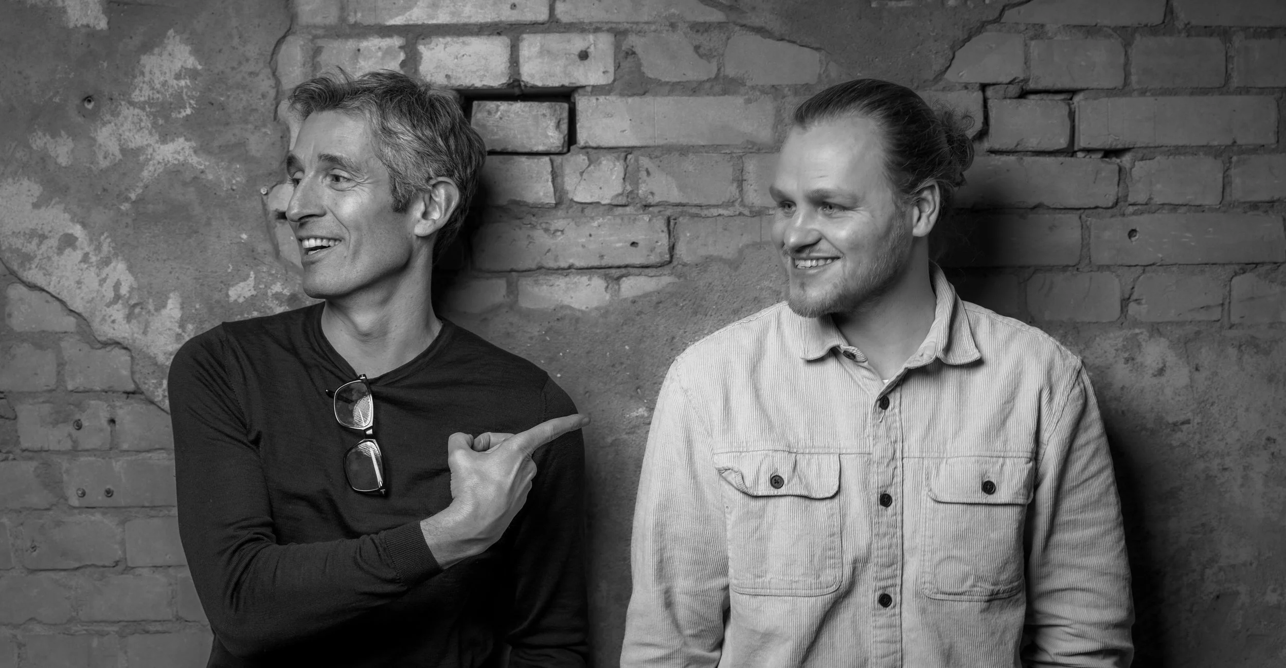 Scenic landscape with mountains, a lake, and grassy hills under a cloudy sky.