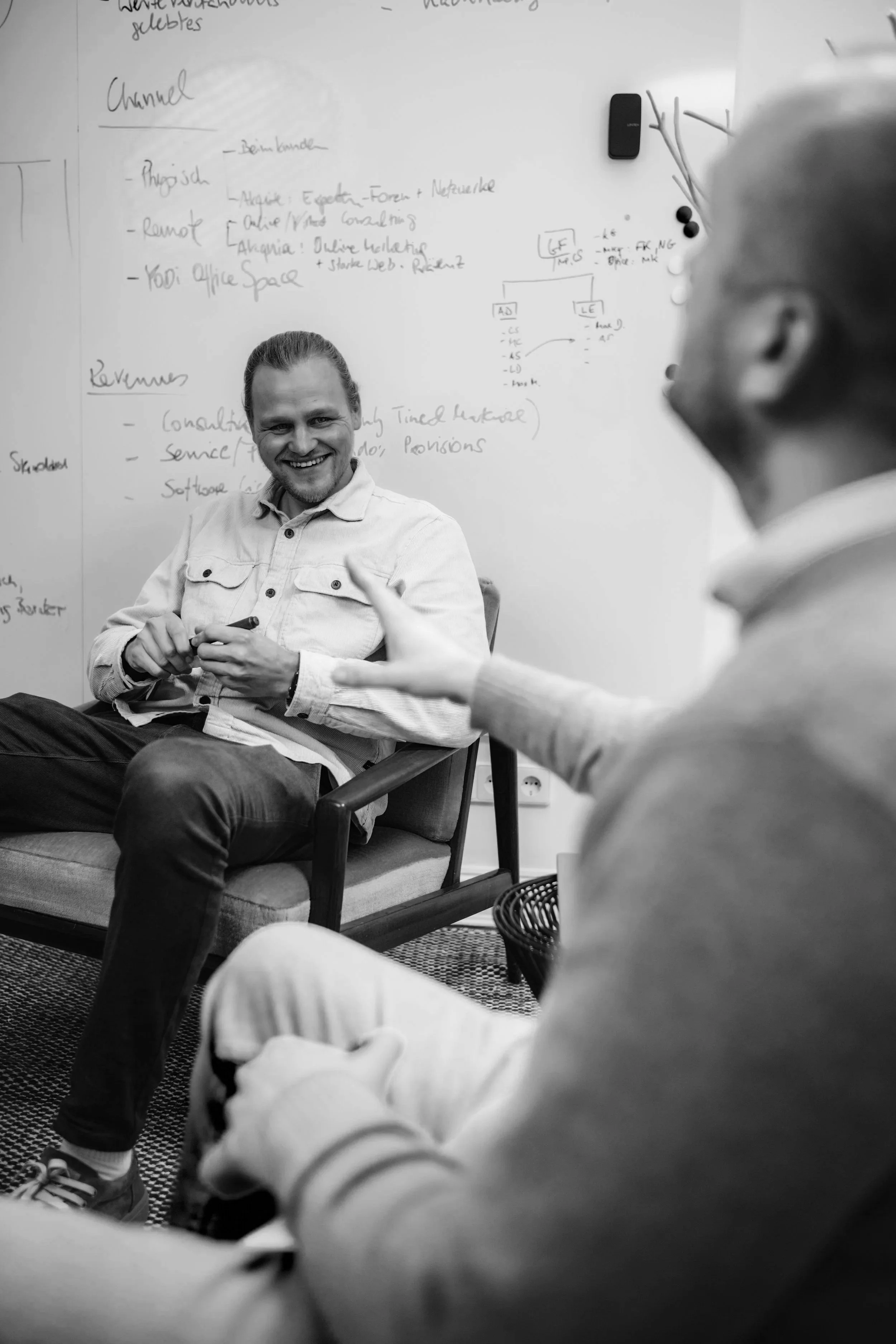 A modern building with wooden exterior panels and large glass window, situated in a mountainous landscape with sparse vegetation.