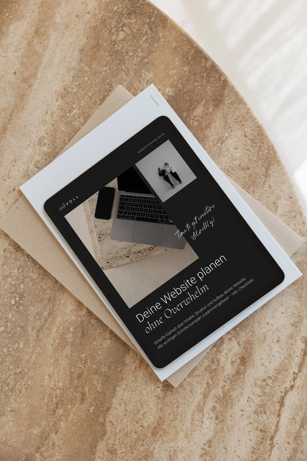 Digitales Magazin auf einem Tablet mit Text über Website-Planung, liegt auf Papier auf einem Steintisch.