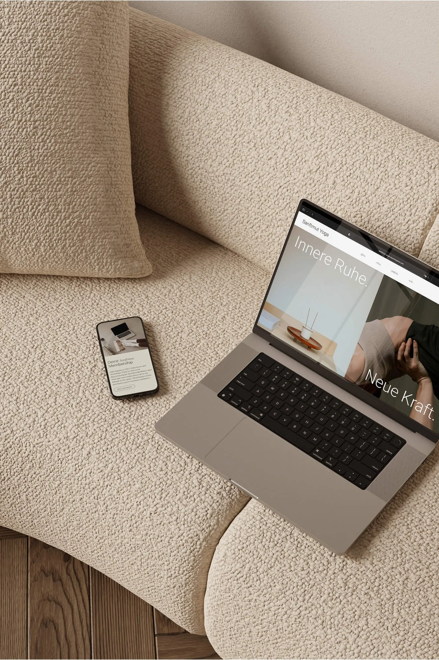 Ein offener Laptop und ein Smartphone auf einer beigefarbenen, gepolsterten Couch. Der Laptop zeigt eine Webseite mit dem Titel 'Innere Ruhe' und das Smartphone zeigt eine Webseite namens 'Deine Sanftmut Membership'.