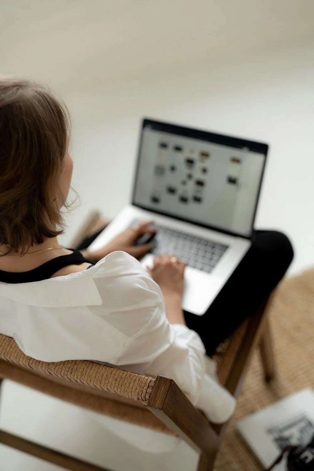 Frau sitzt auf einem Stuhl und schaut auf einen Laptop-Bildschirm, der ein Website-Design zeigt.