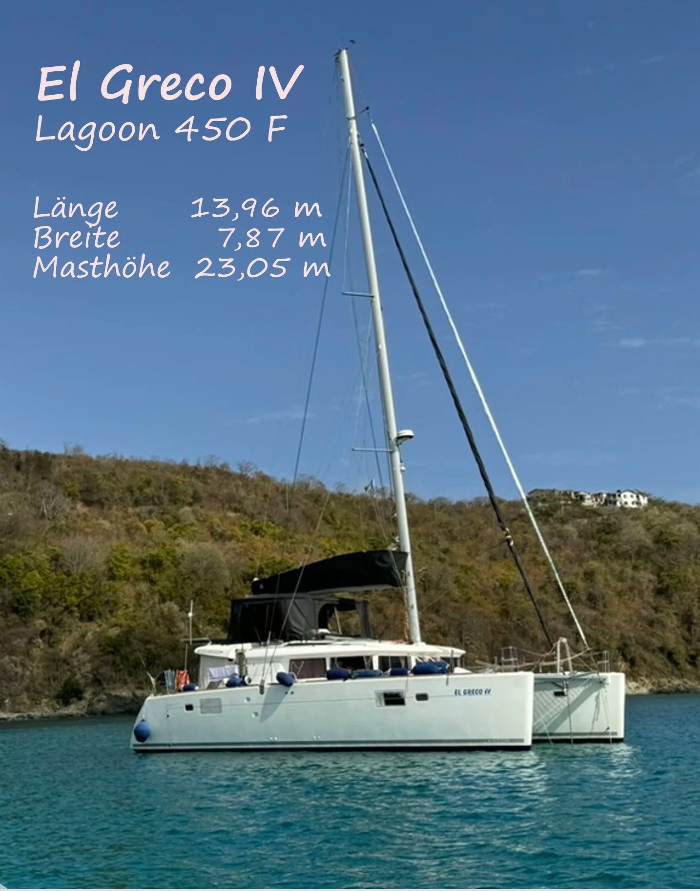 Segelboot namens El Greco IV auf dem Wasser vor einer hügeligen Landschaft mit Gebäuden im Hintergrund, weißes Boot mit schwarzem Mast und blauen Fendern, blauer Himmel, Wasser im Vordergrund.