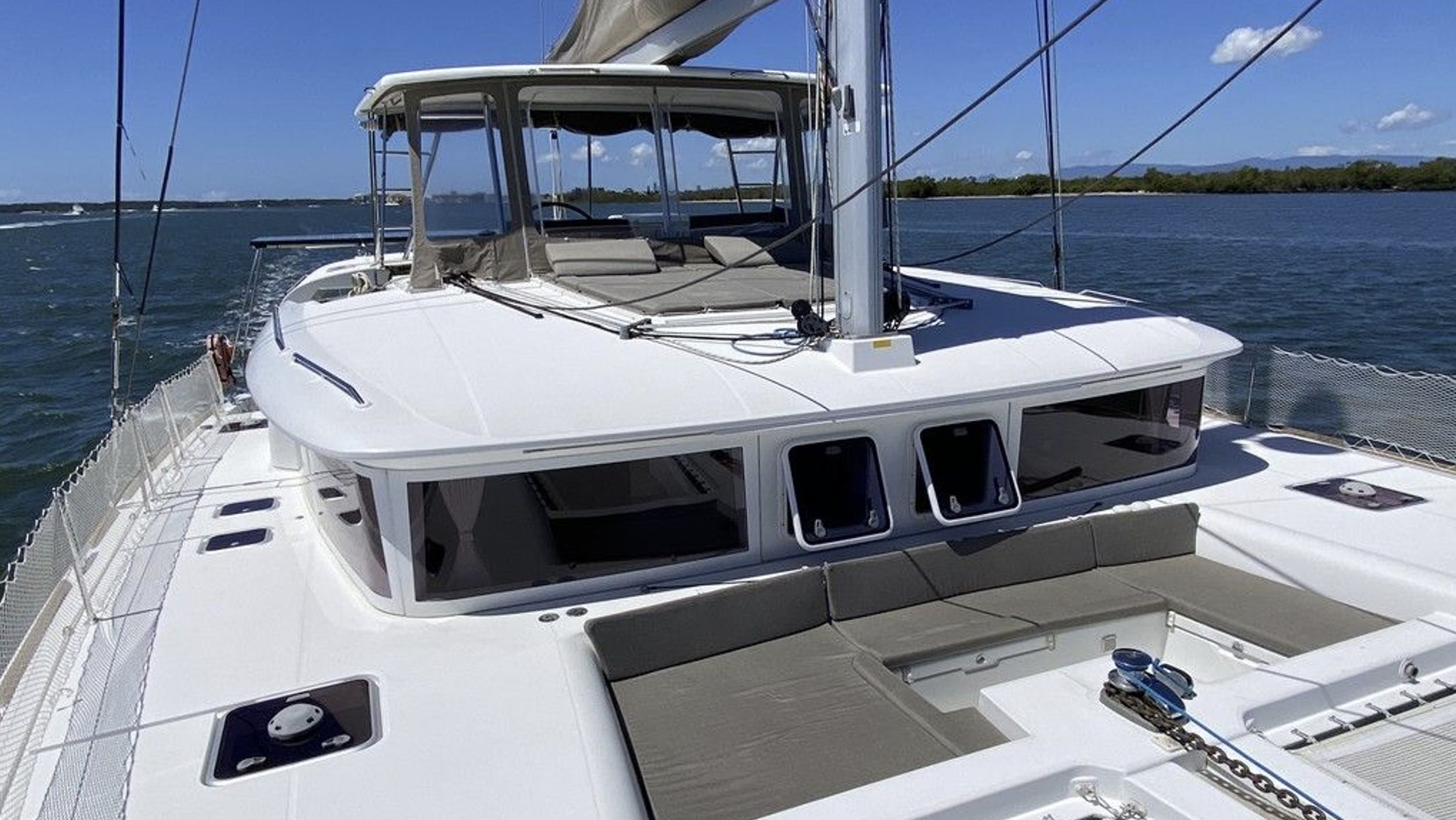 Weiße Yacht mit Sonnenliegen auf dem Deck, Wasser und Himmel im Hintergrund.
