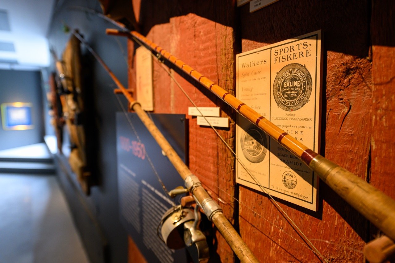To vintage fiskestenger utstilt på en vegg medinformasjon og gamle fiskereklammer.