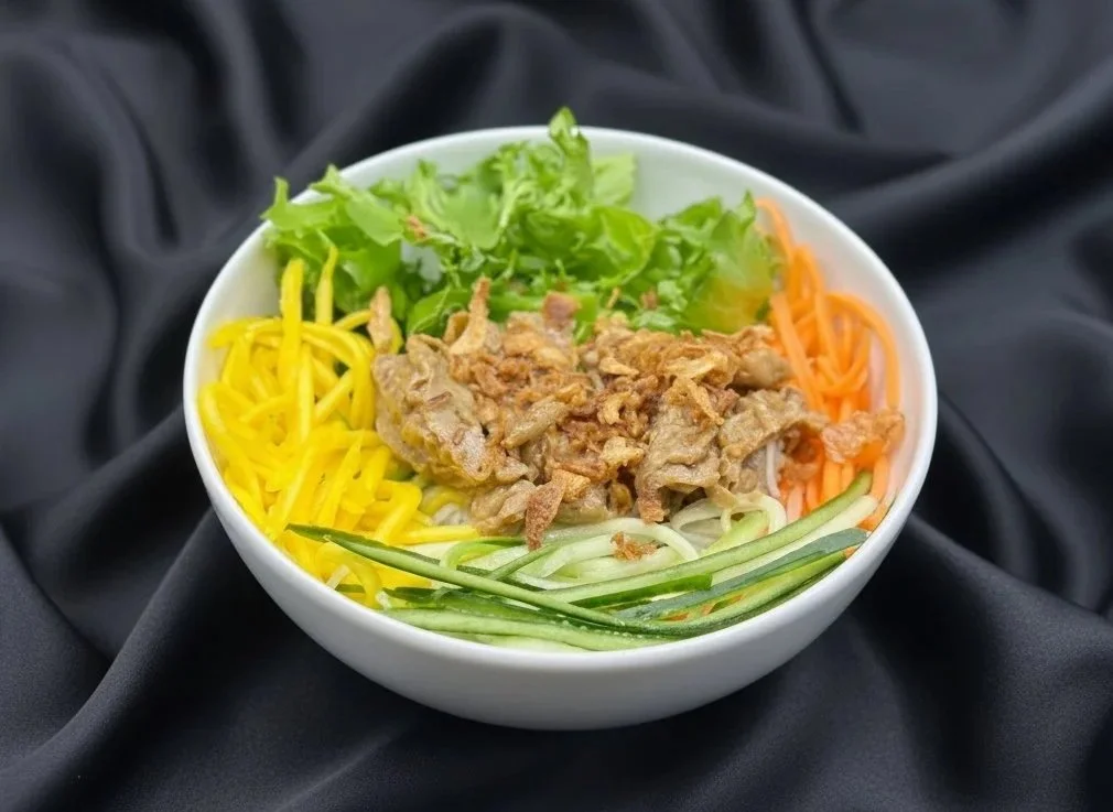 A bowl of various fresh vegetables and meat substitutes, including carrots, cucumber, lettuce, and some crispy mechanical strips, served on a black background.