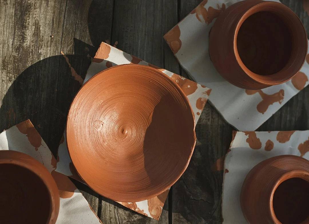 Ceramic pottery pieces on wooden table with some wrapped paper