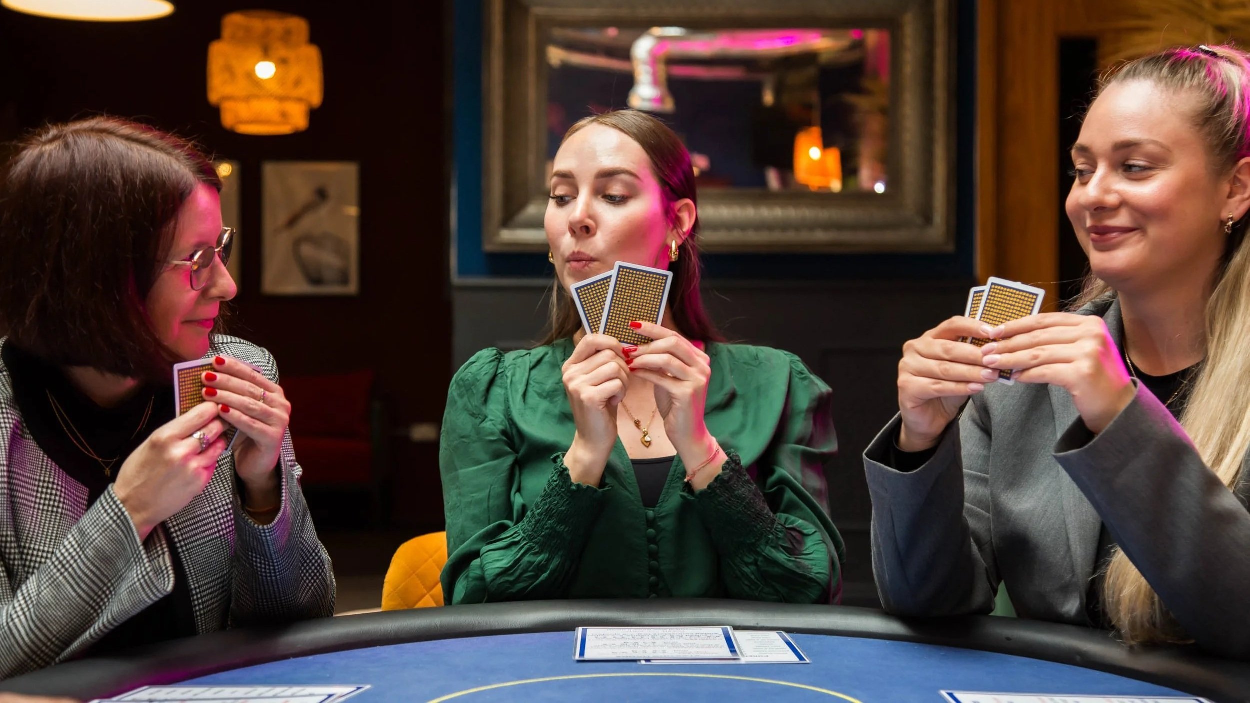 Three women playing cards at a poker in a Aces High London strategic decision-making training workshop