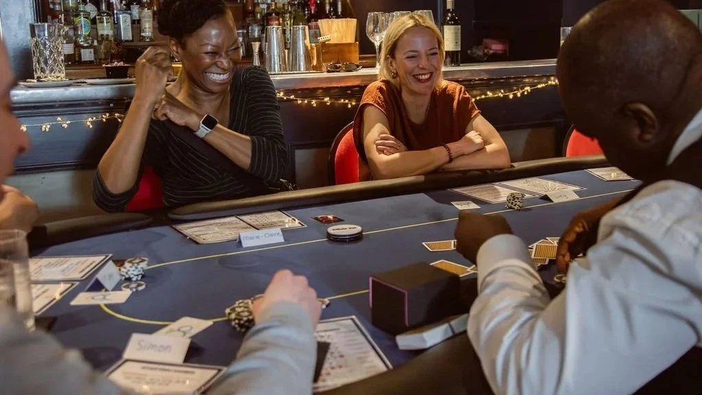 Colleagues laughing around an Aces High poker table