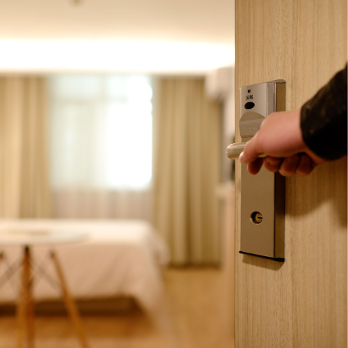 Une personne insère une clé dans une serrure de porte dans une chambre d'hôtel ou une pièce similaire.