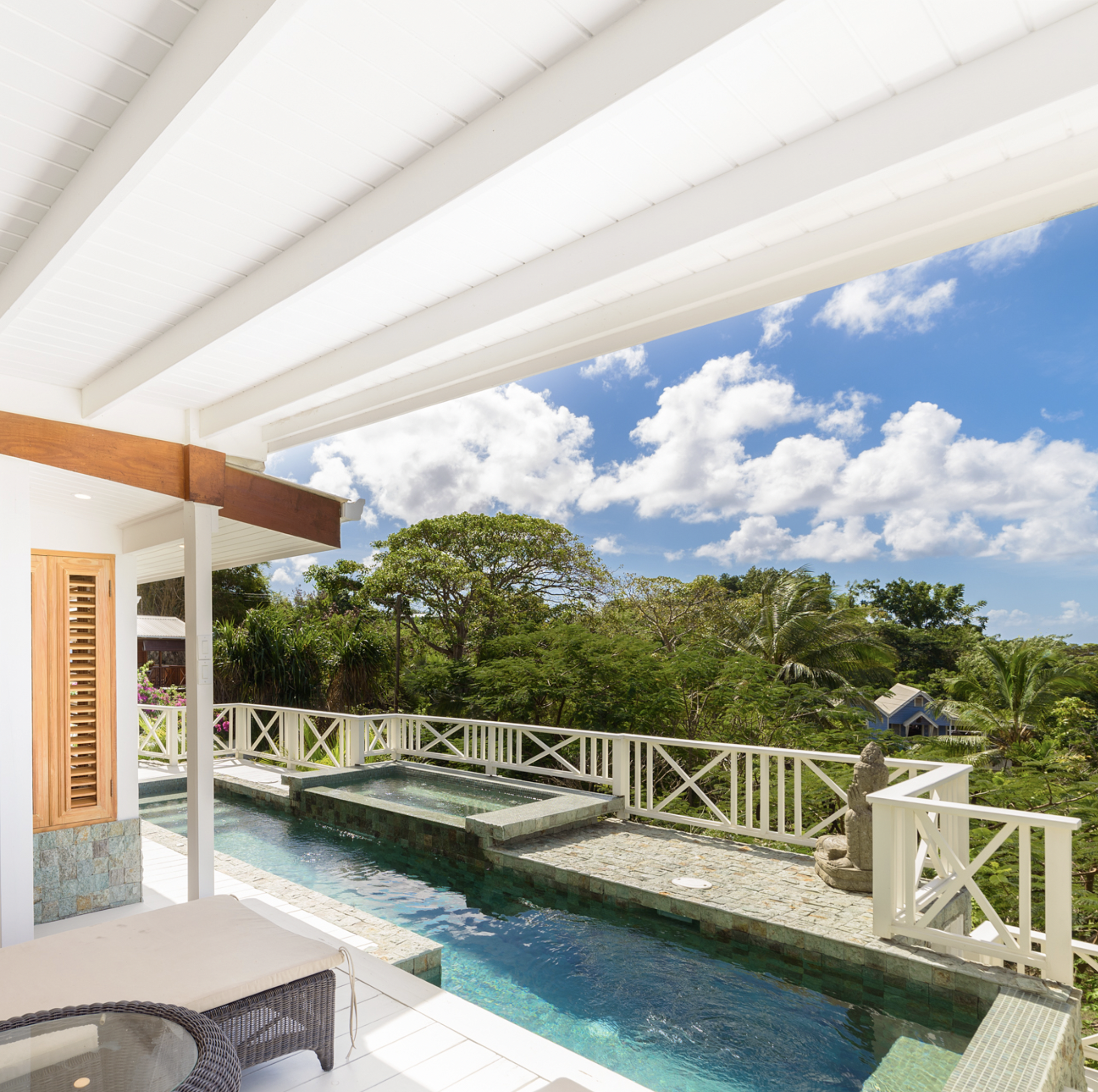 Huge veranda with pool and hot tub, surrounded by overlooking lush green trees and endless sea views.