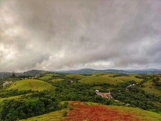 A landscape with rolling green hills under a cloudy sky.