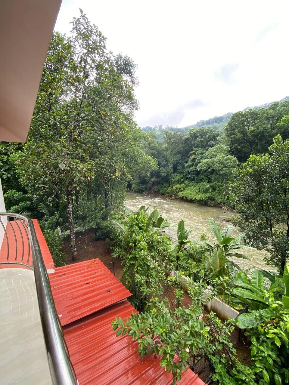 View from a balcony overlooking a river surrounded by lush green trees.