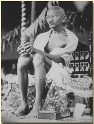 A man sitting outdoors, holding a guitar, dressed in traditional clothing, with a natural background and decorative elements.